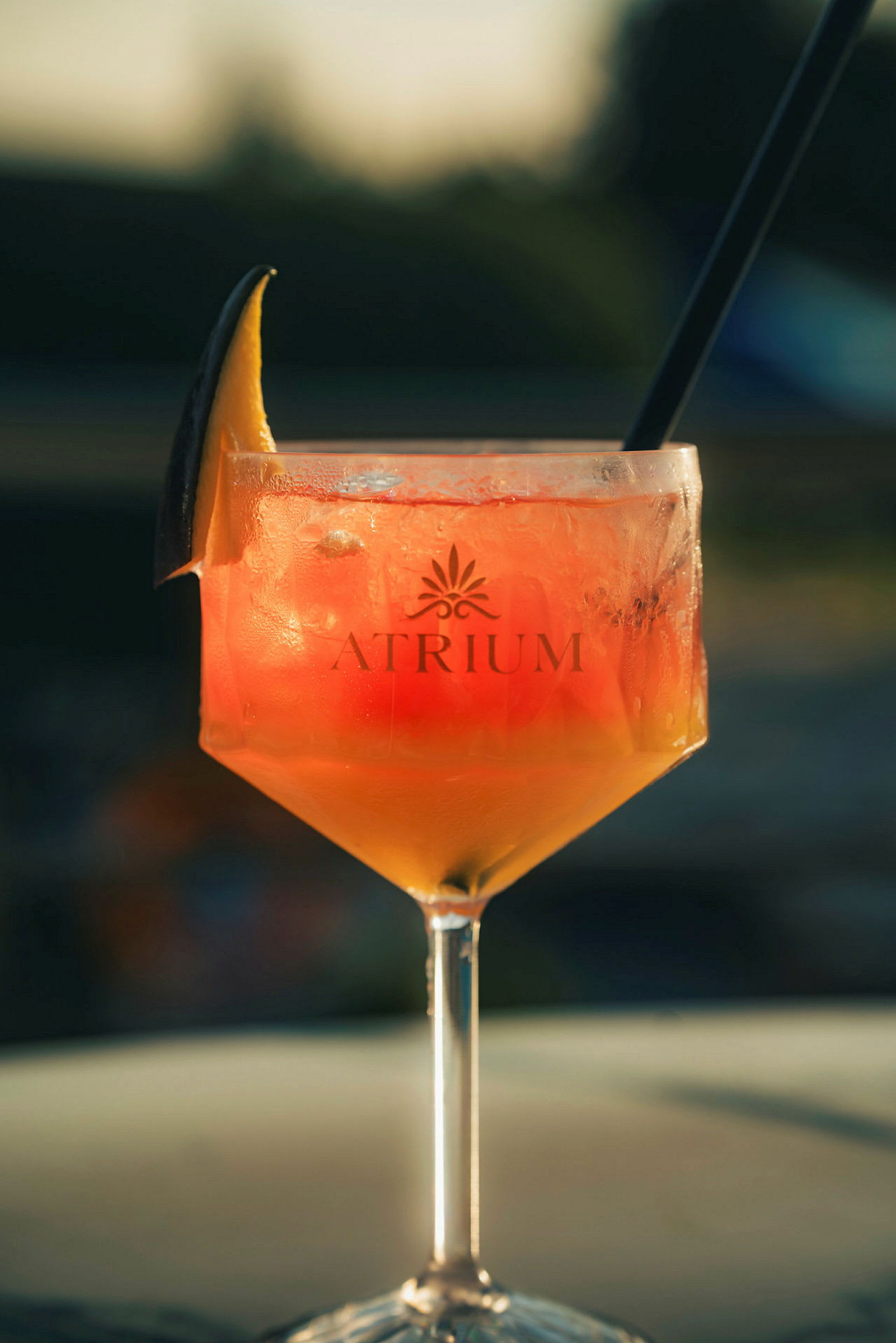 Ett glas med en orangefärgad drink och isbitar, dekorerad med en skiva citrusfrukt på kanten. (AI-genererad text)