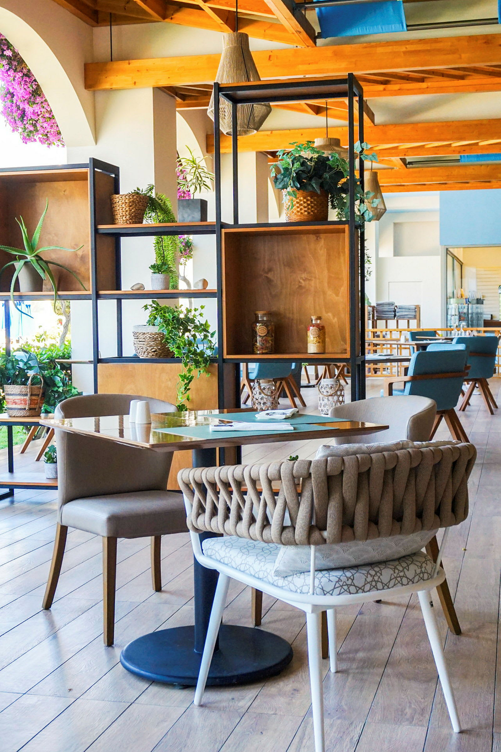 Bild av ett elegant inrett kafé eller restaurang, med moderna möbler, trädetaljer och dekorationer i form av gröna växter. (AI-genererad text)