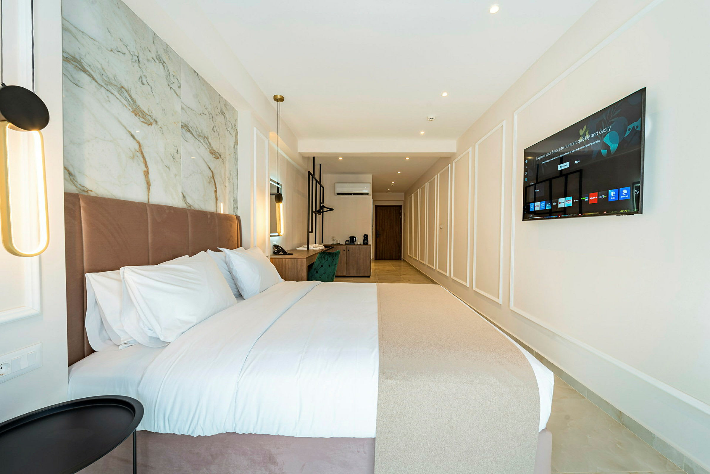 Hotellrum med en stor säng, skrivbord och väggmonterad TV. (AI-genererad text)