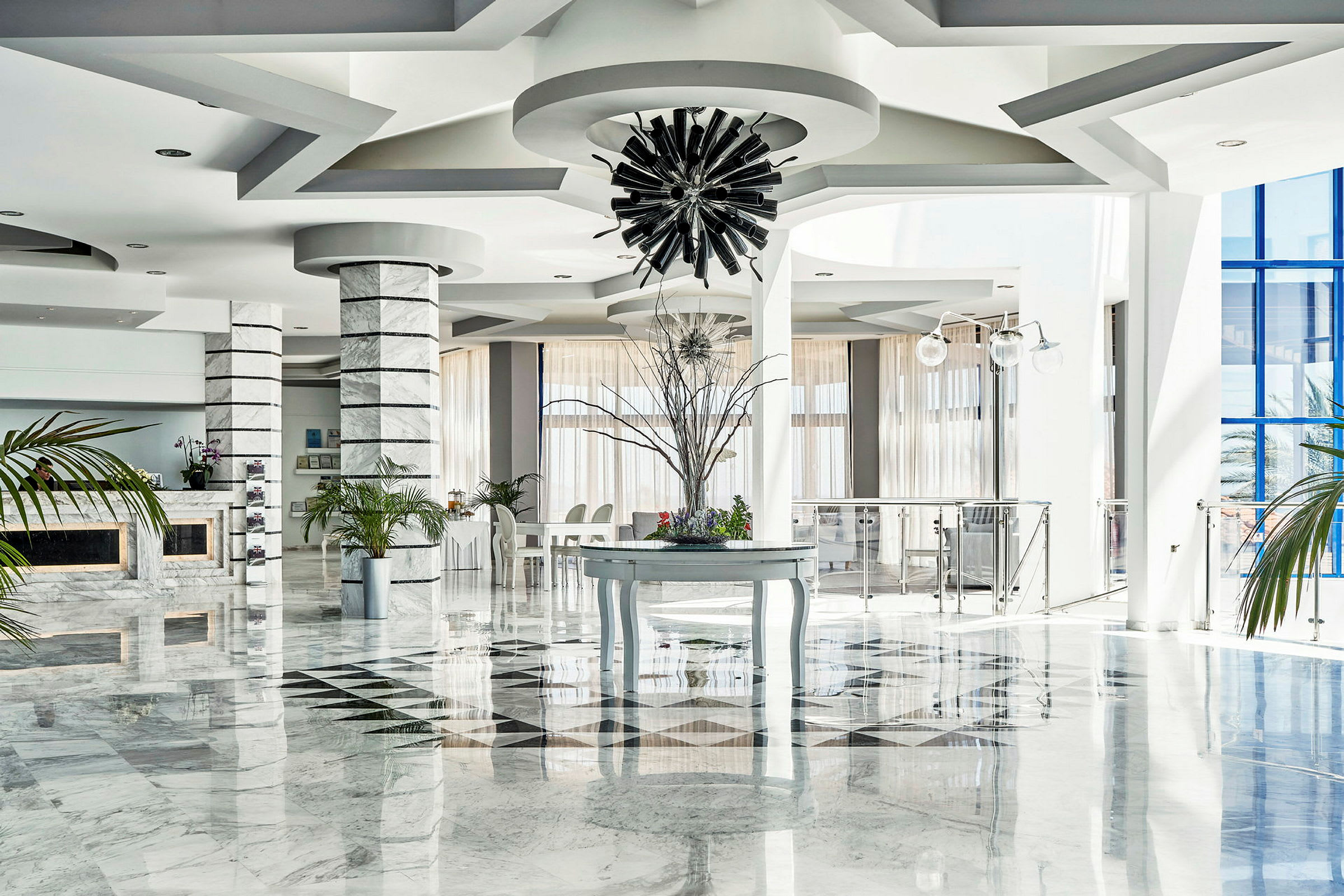 Interiör av en ljus hotellobby med marmorgolv, dekorativa pelare och modern inredning. (AI-genererad text)