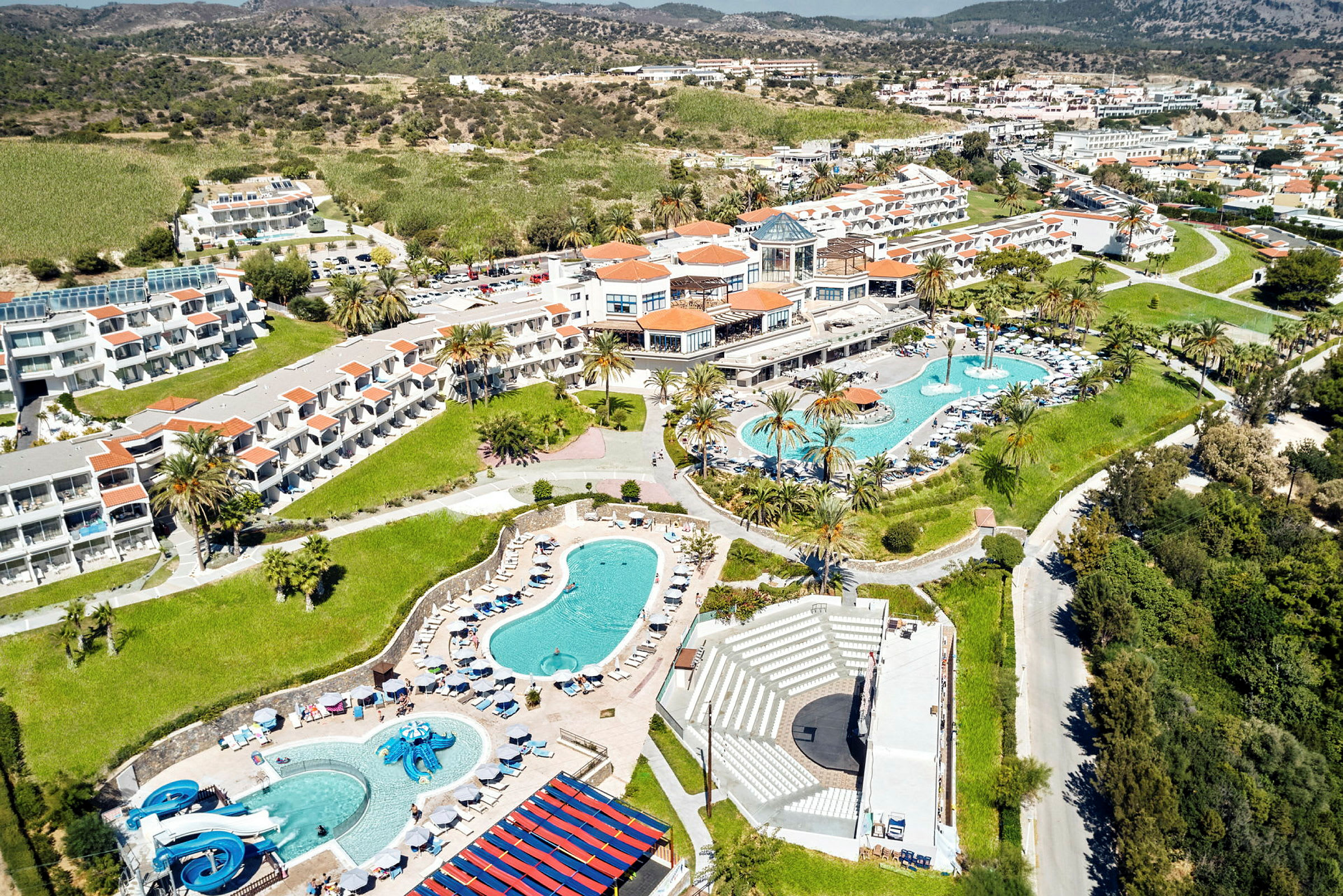 Flygfoto av en resort med pooler, byggnader och grönområden. (AI-genererad text)