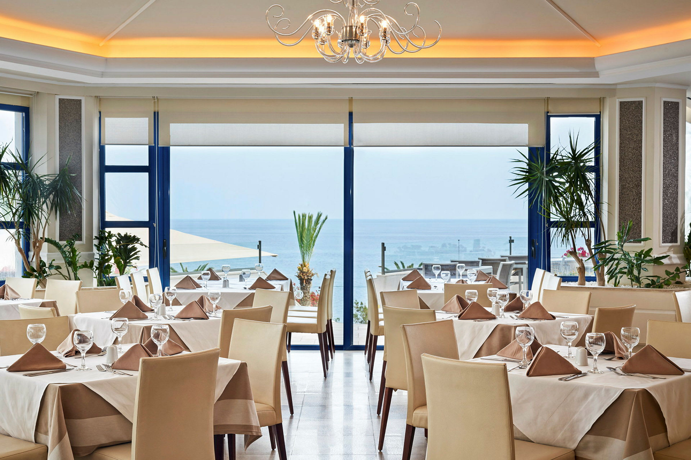 Restaurang med dukade bord, stora fönster och havsutsikt. (AI-genererad text)