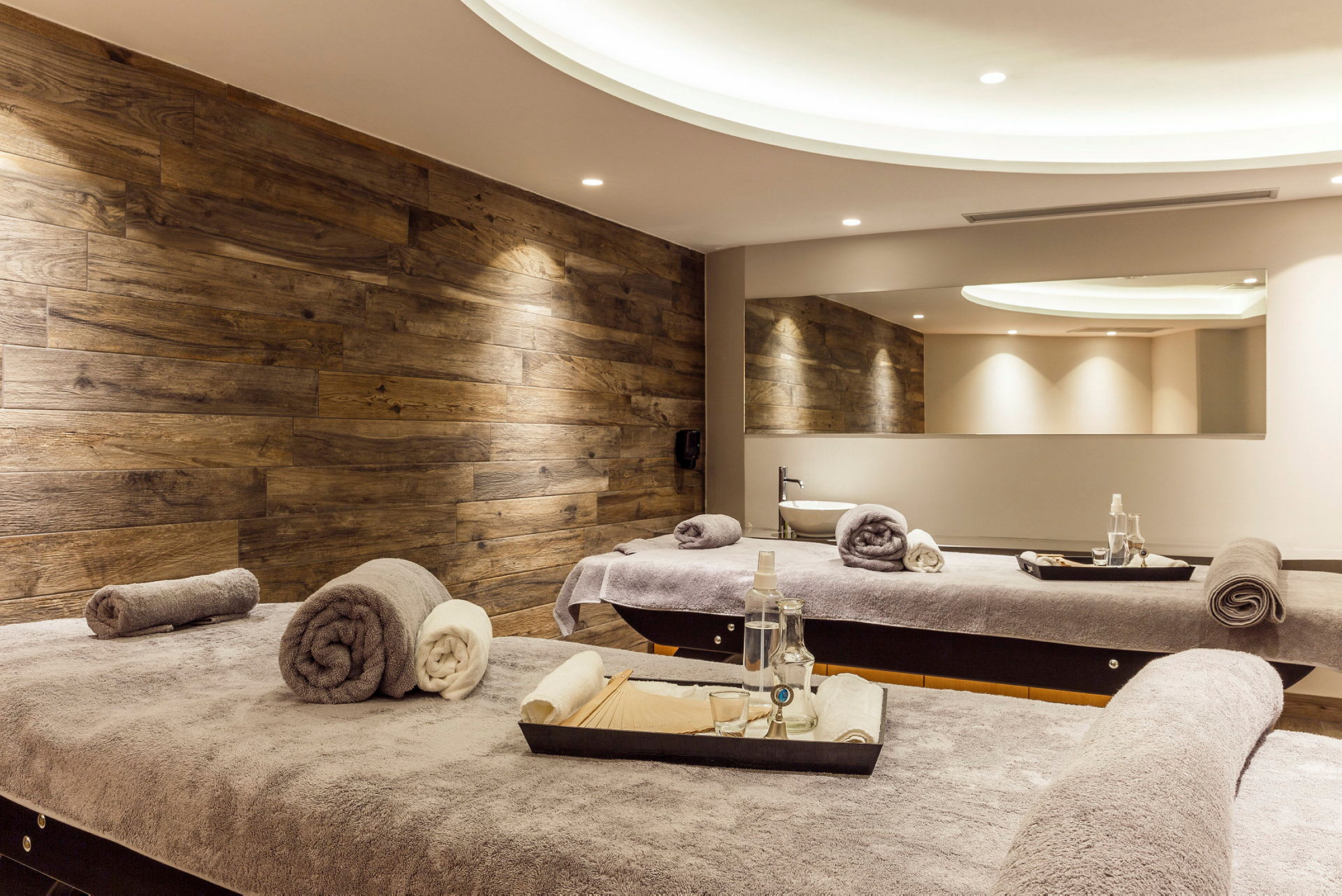 Bild på ett spa-rum med massagebord, handdukar och träpaneler. (AI-genererad text)