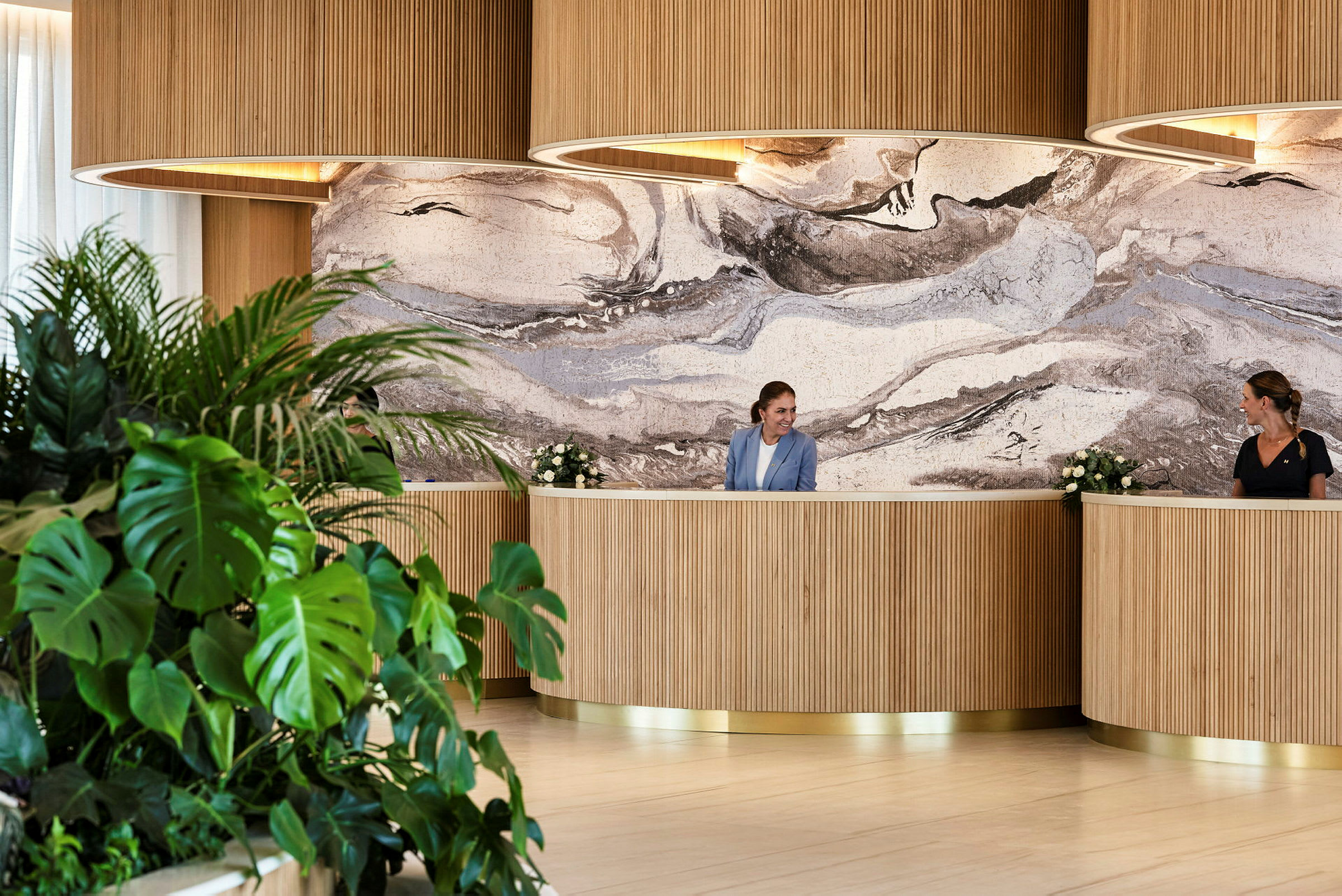 Receptionen med två personer vid disken samt växter i förgrunden. (AI-genererad text)
