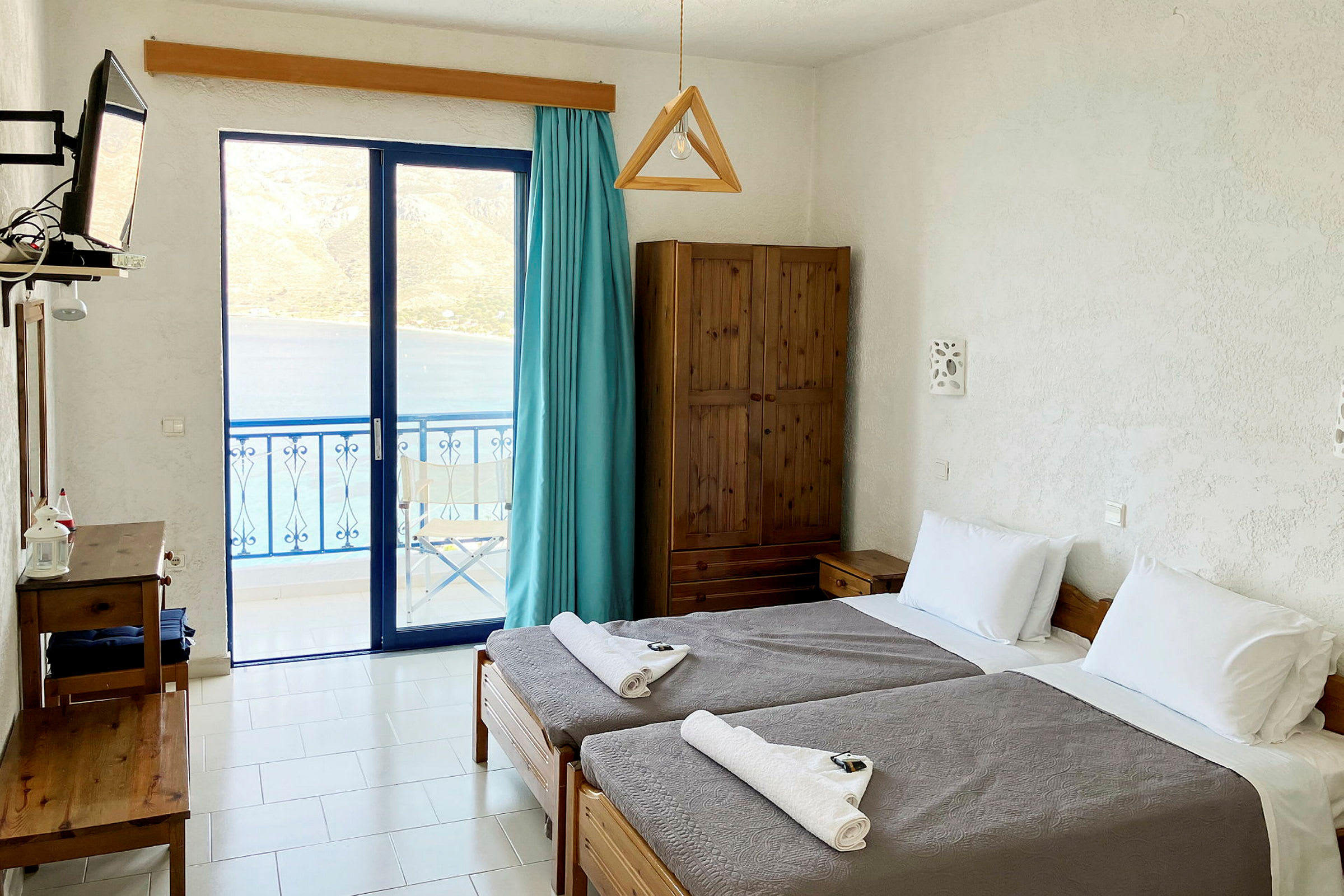 Ett hotellrum med två enkelsängar och utsikt över havet genom glasdörrar. (AI-genererad text)
