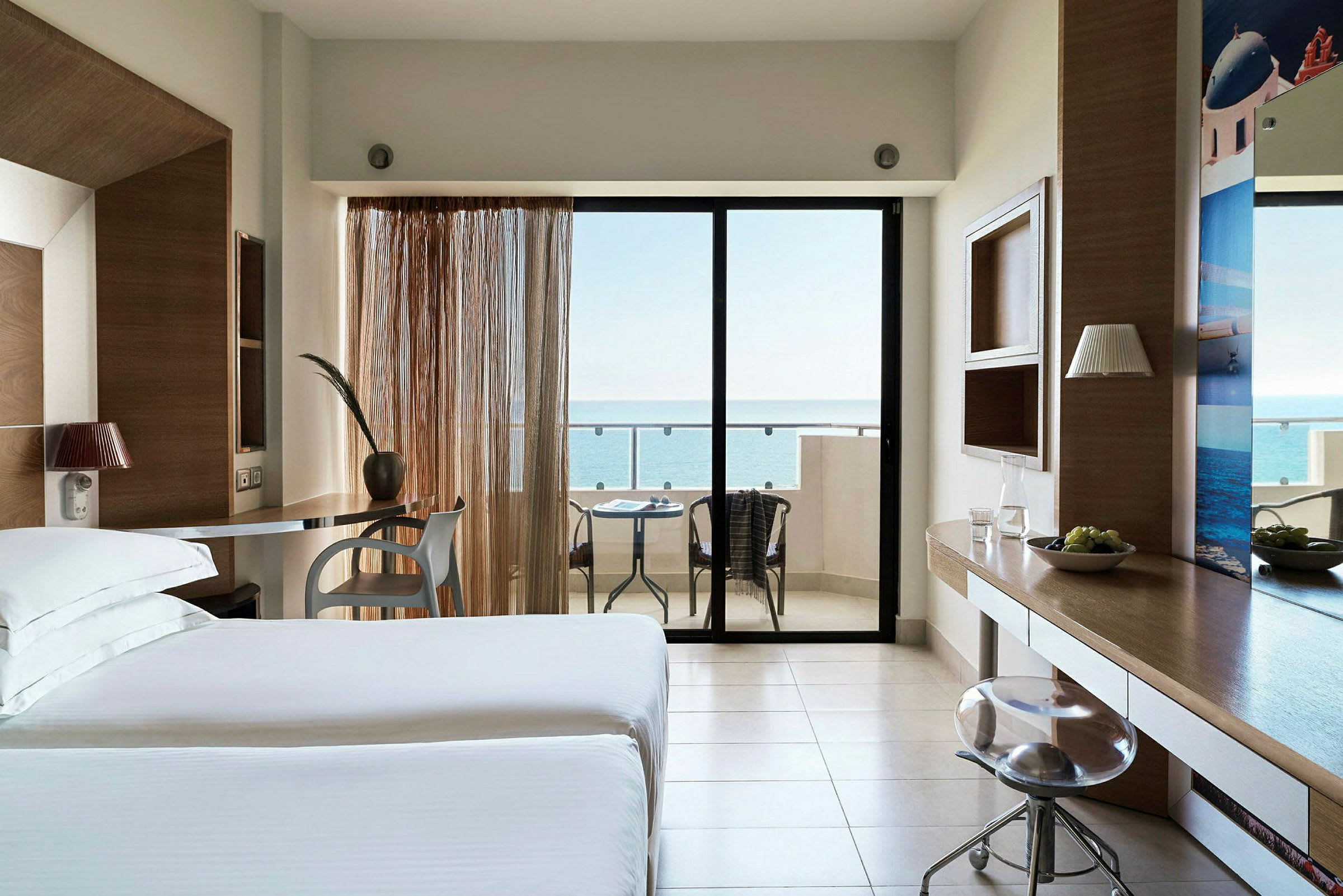 Hotellrum med modern inredning, sittgrupp och balkong med havsutsikt. (AI-genererad text)
