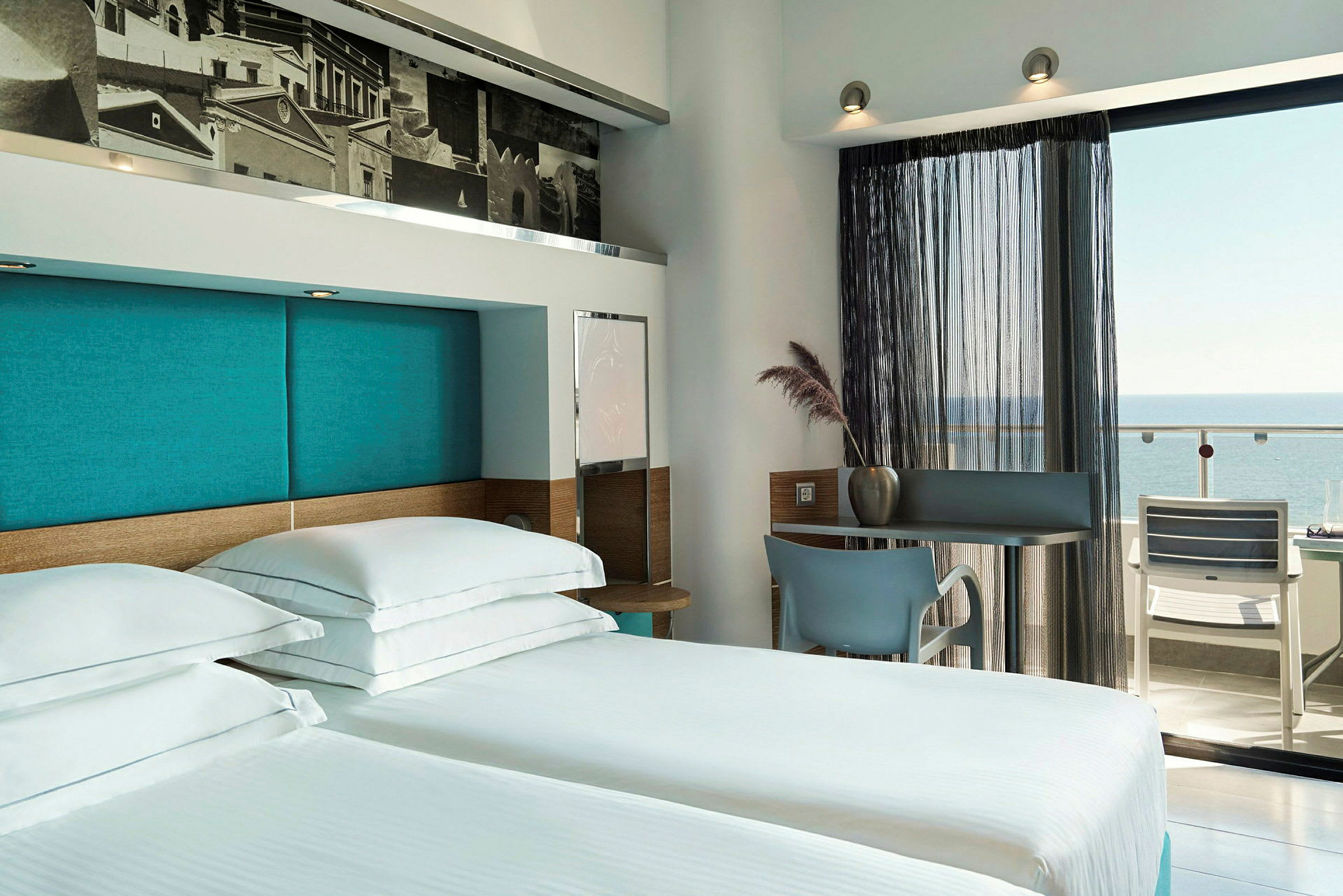 Hotellrum med två sängar och utsikt mot balkongen med havet i förgrunden. (AI-genererad text)