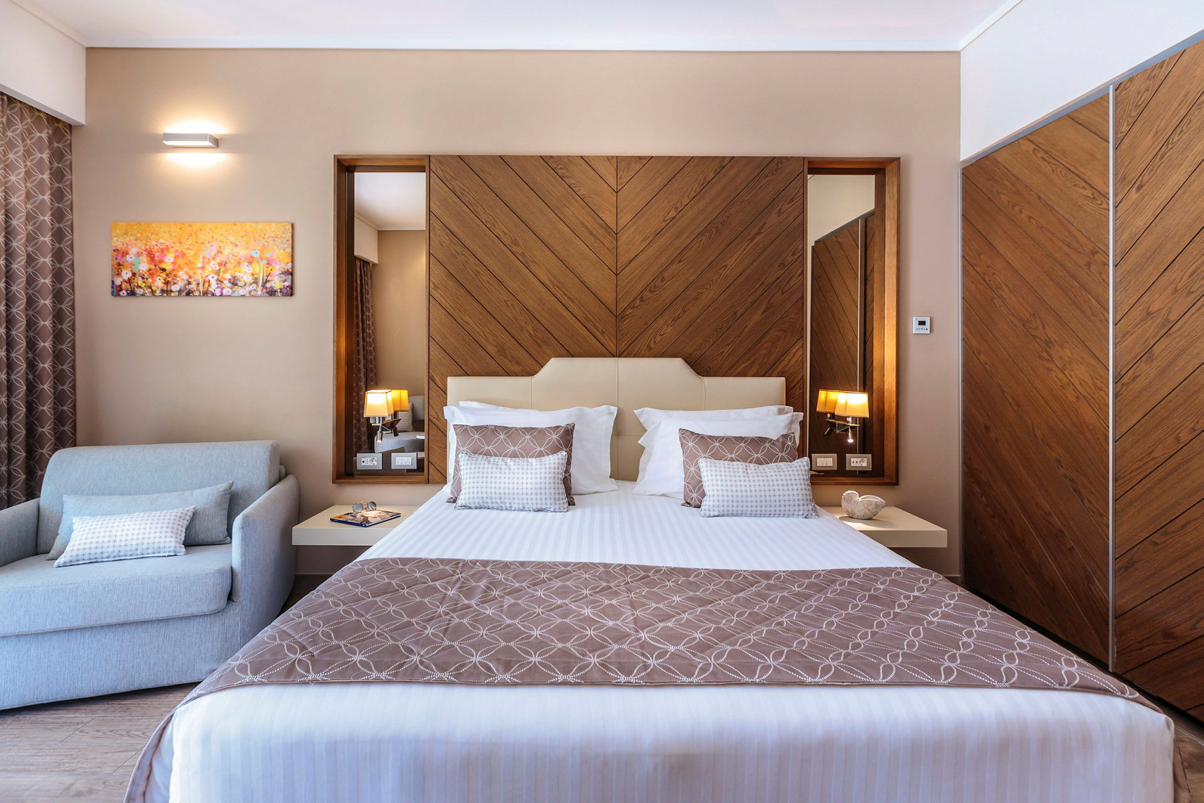 Ett modernt hotellrum med en säng, en fåtölj och träinredningsdetaljer. (AI-genererad text)