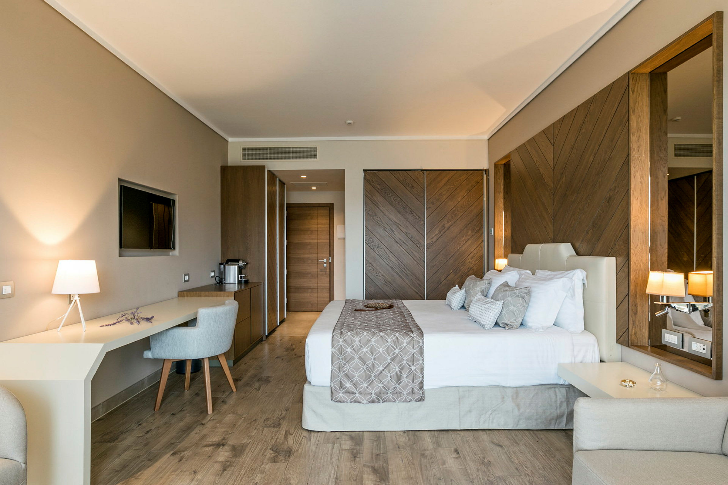 Ett hotellrum med en dubbelsäng, ett skrivbord med stol och en TV på väggen. (AI-genererad text)