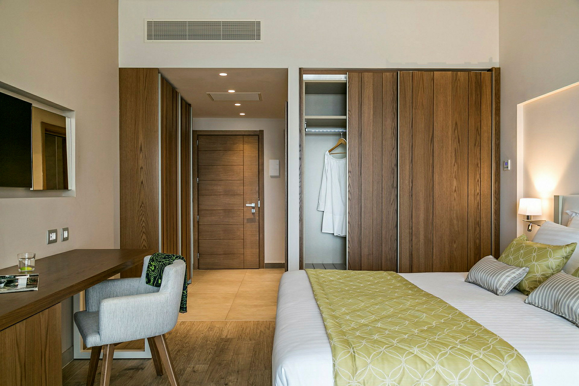 Ett hotellrum med en säng, ett skrivbord med stol och garderob. (AI-genererad text)