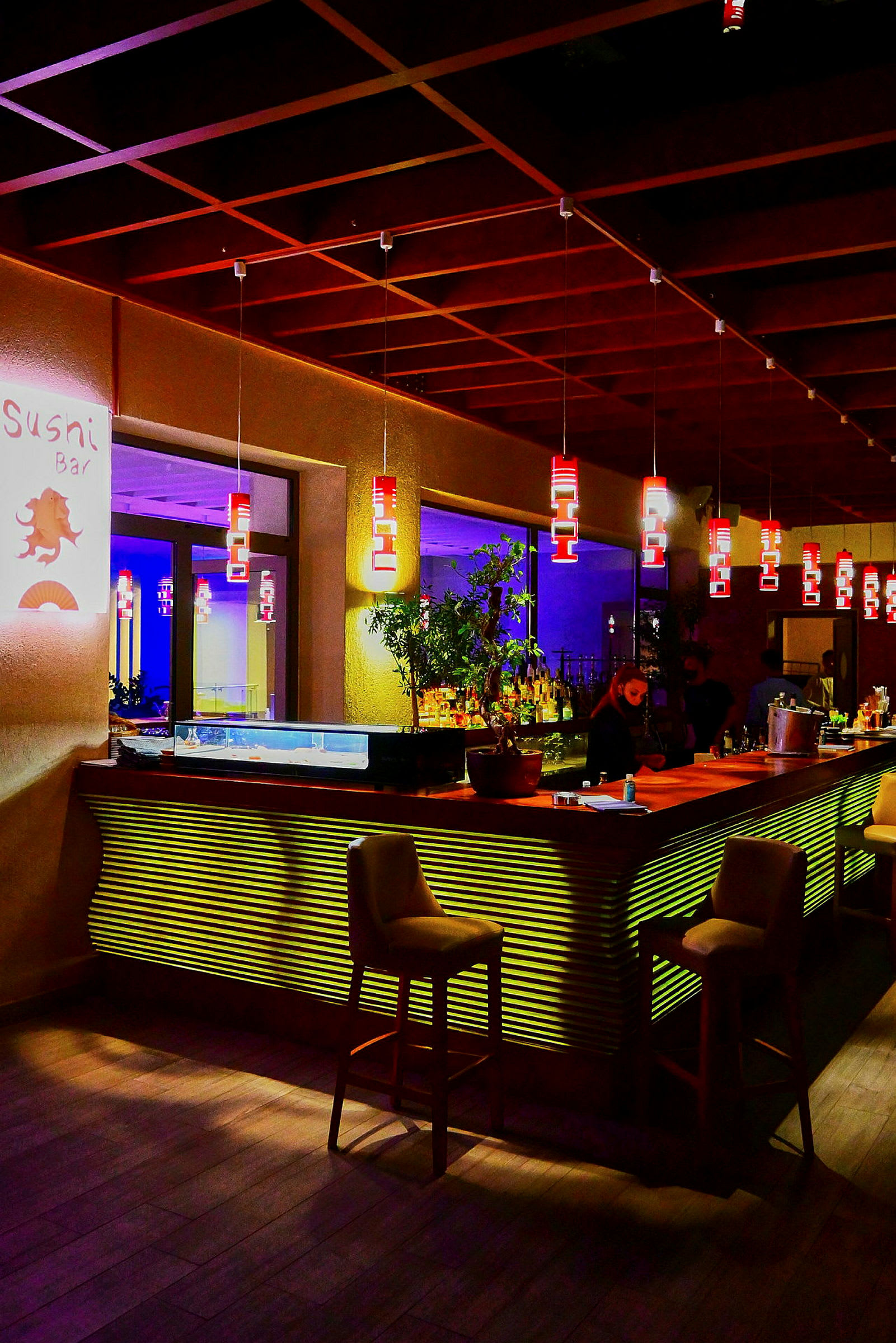 En modern sushi-bar med mysig belysning och stolar runt bardisken. (AI-genererad text)
