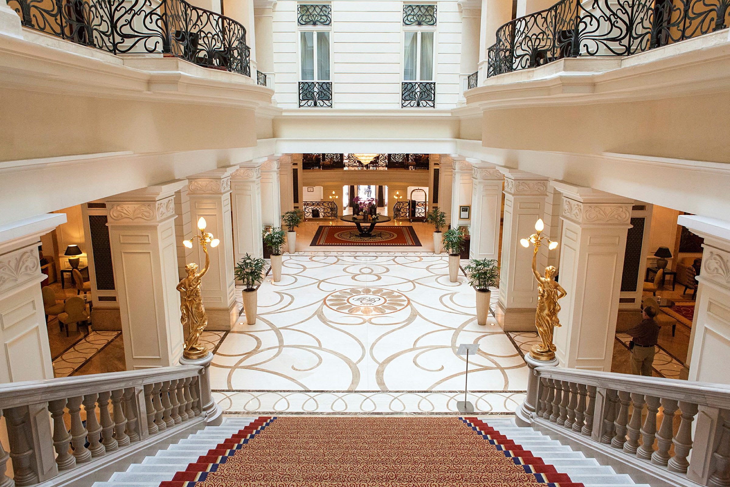 Interiör av ett elegant hotell, med trappa, dekorativa väggar och guldstaty. (AI-genererad text)