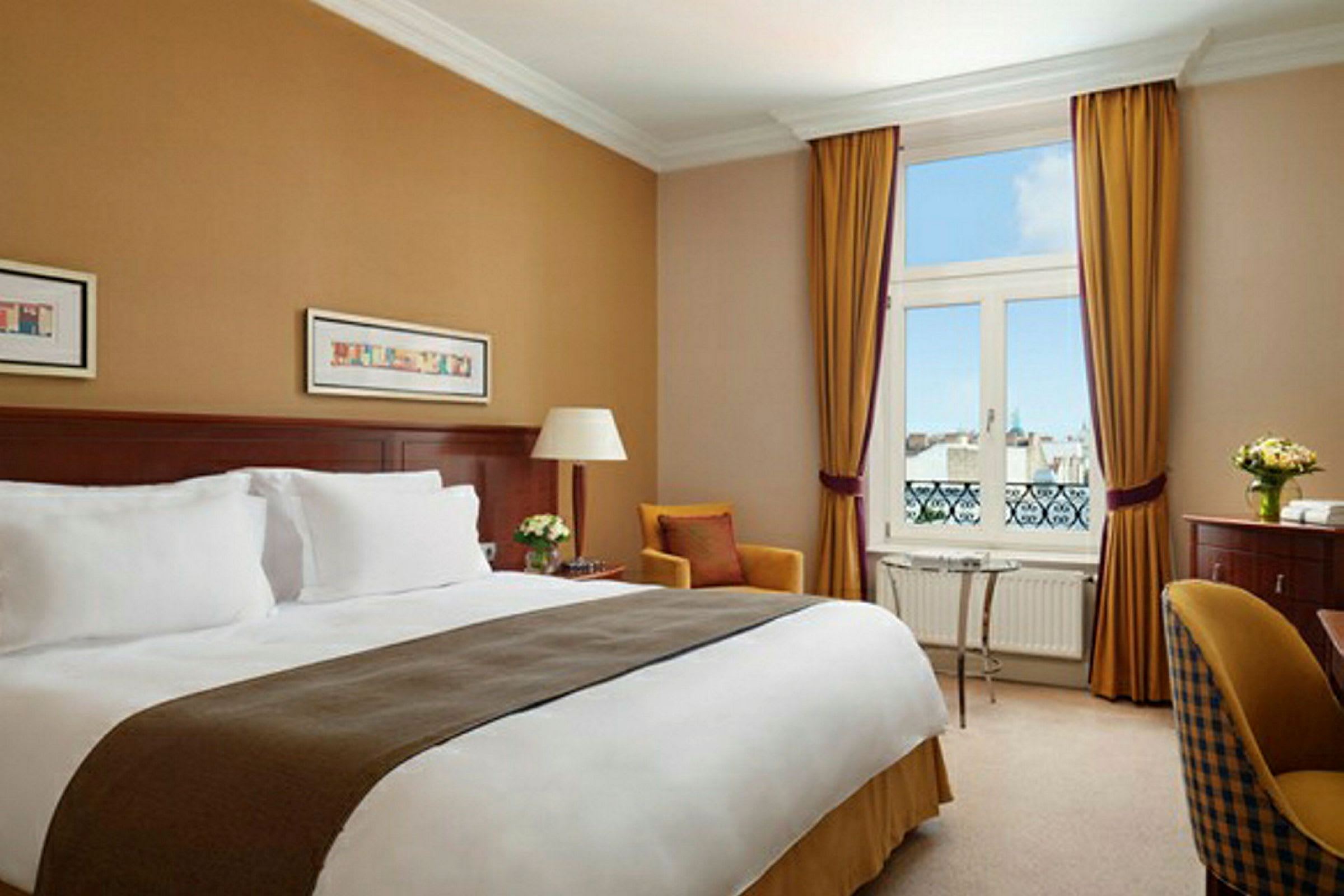 Ett hotellrum med en dubbelsäng, sittmöbler och utsikt genom ett fönster. (AI-genererad text)