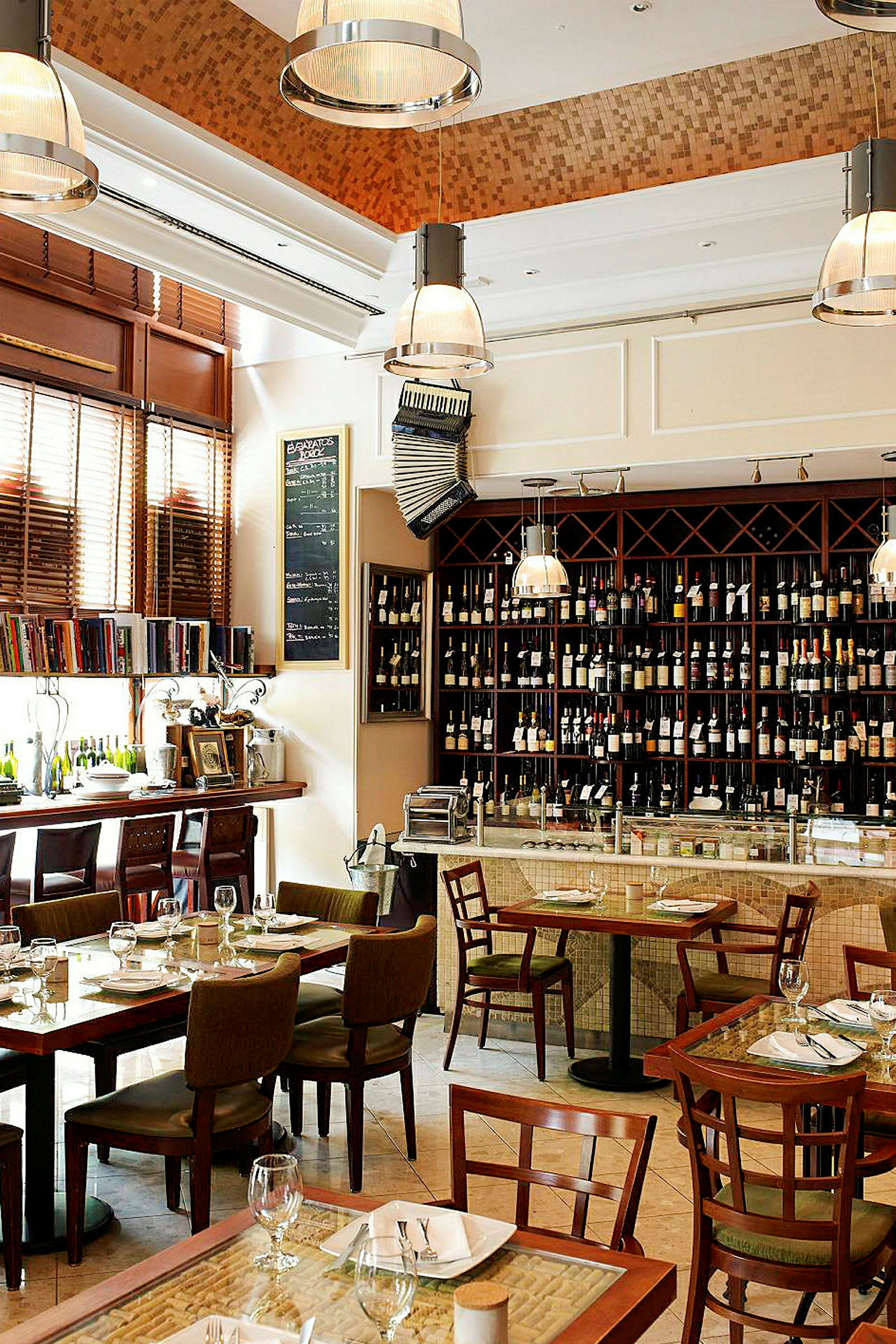 Interiör av en restaurang med matbord och stolar, en hylla med vinflaskor och en bardisk. (AI-genererad text)