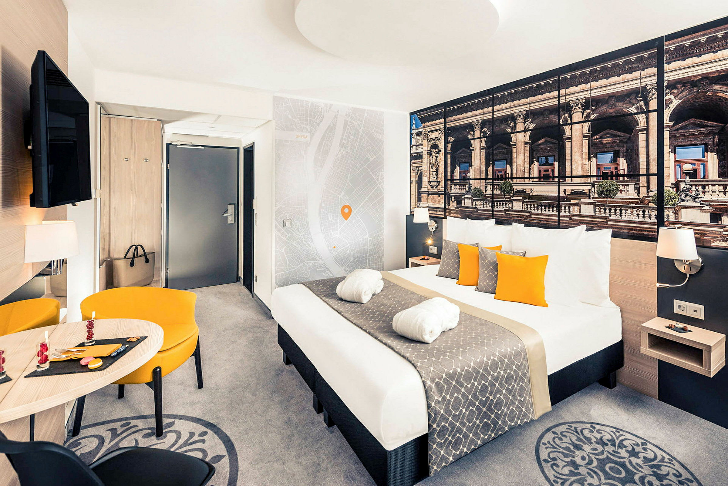 Ett hotellrum med en dubbelsäng, matsalsmöbler och väggdekorationer. (AI-genererad text)