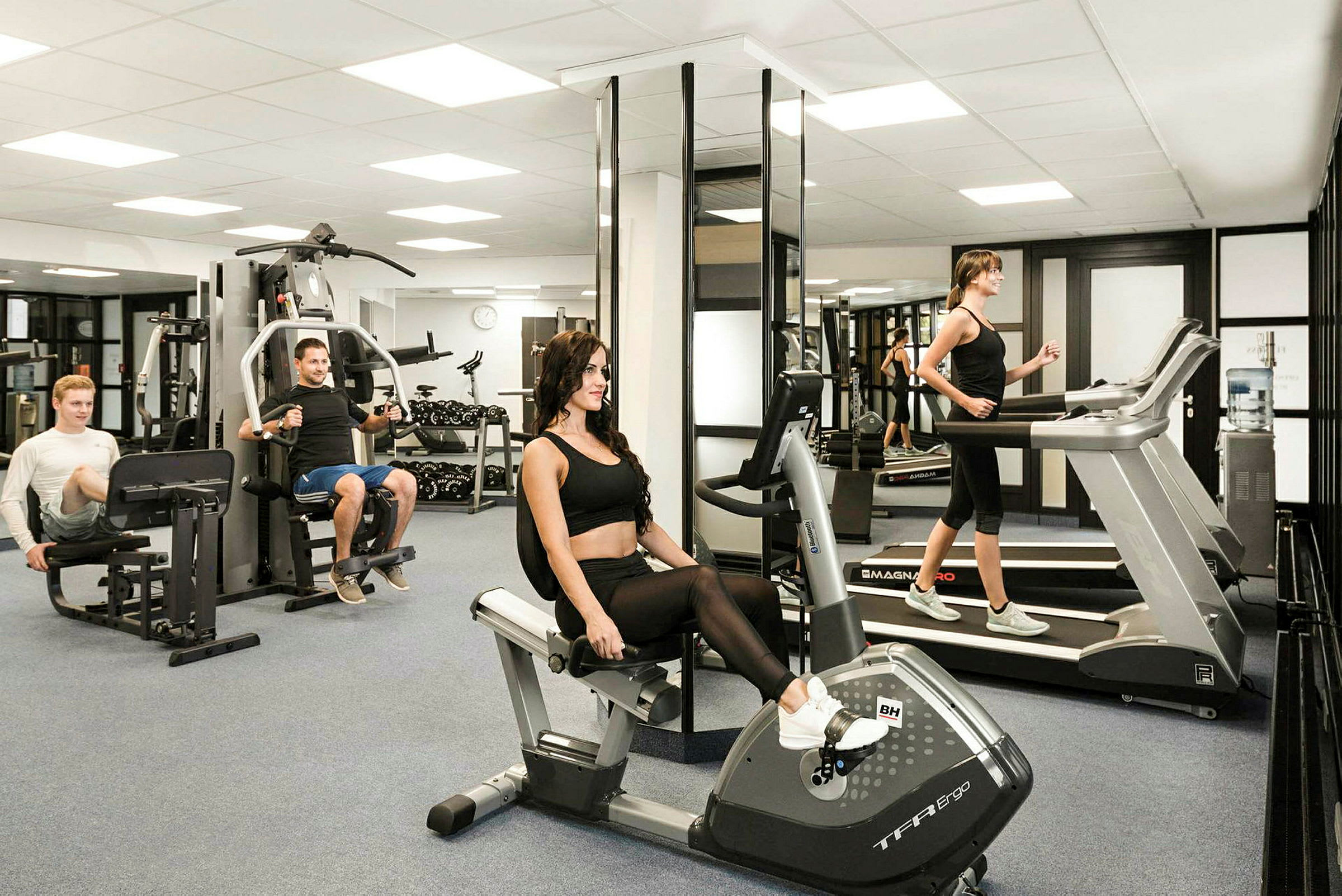 Ett gym med träningsutrustning som cykel, löpband och styrketräningsmaskiner. (AI-genererad text)