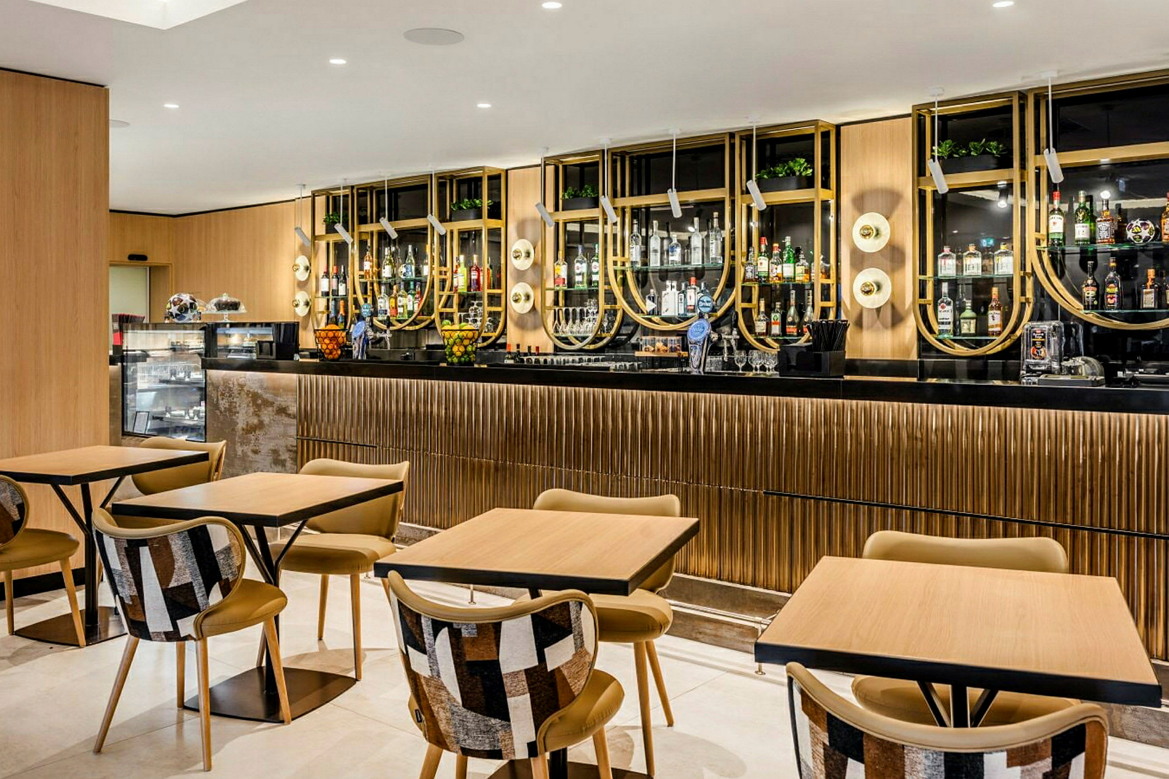En modern bar och café med stilfulla bord och stolar, samt en elegant och välorganiserad drinkhylla i bakgrunden. (AI-genererad text)