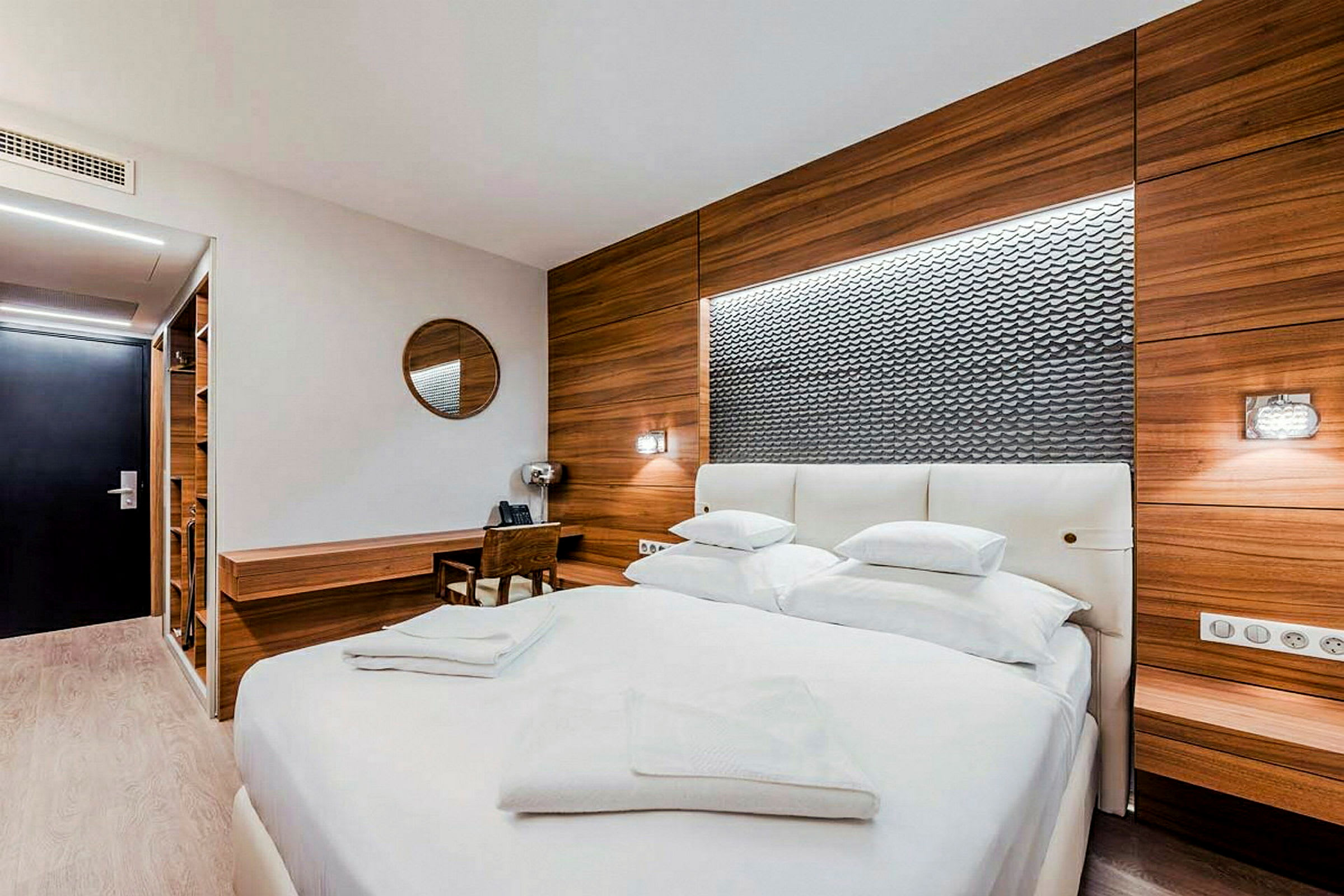 Ett modernt hotellrum med en stor dubbelsäng, trädetaljer på väggarna och en skrivbordsyta. (AI-genererad text)