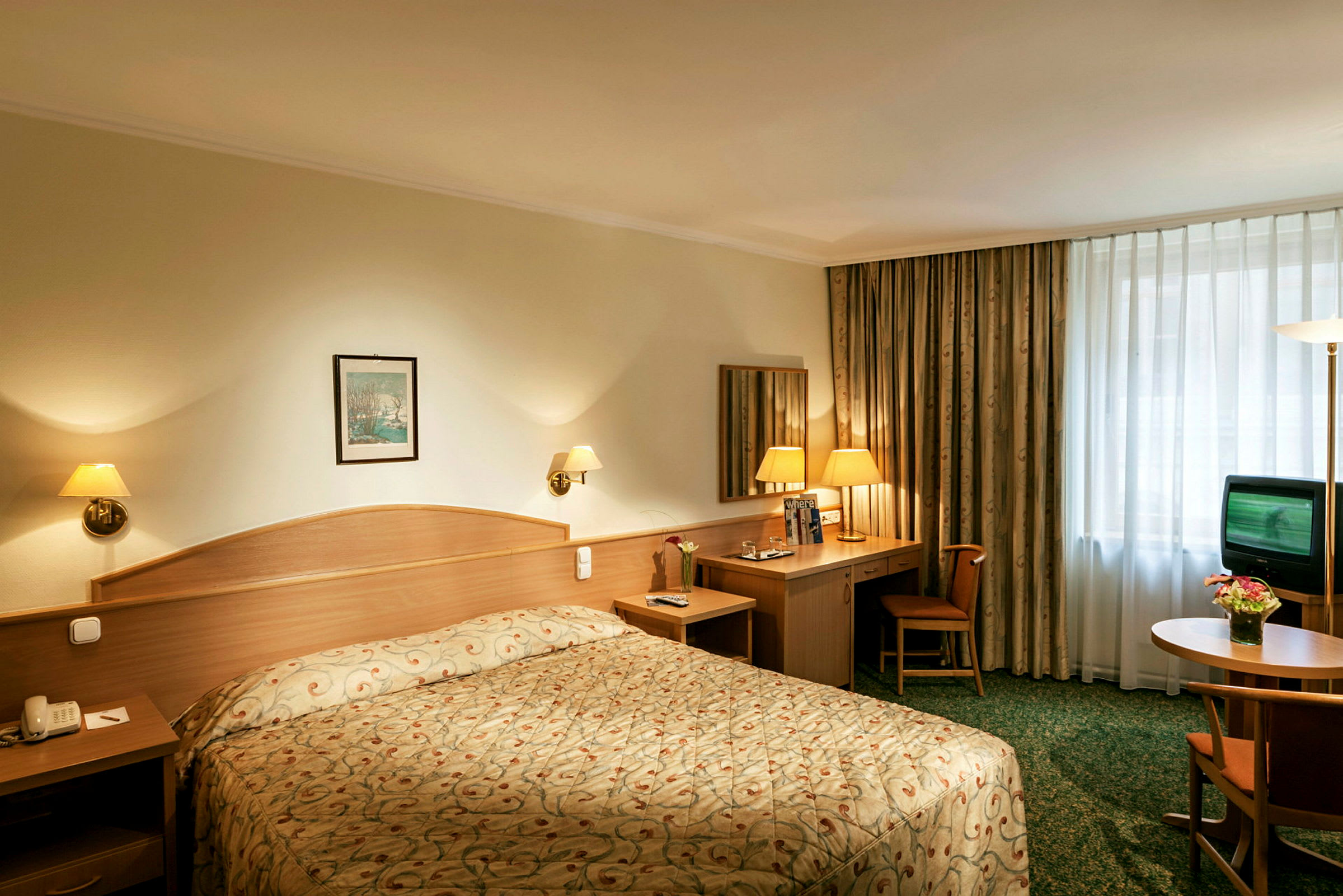 Interiör av ett hotellrum med en dubbelsäng, skrivbord och stol, samt en TV på en byrå. (AI-genererad text)