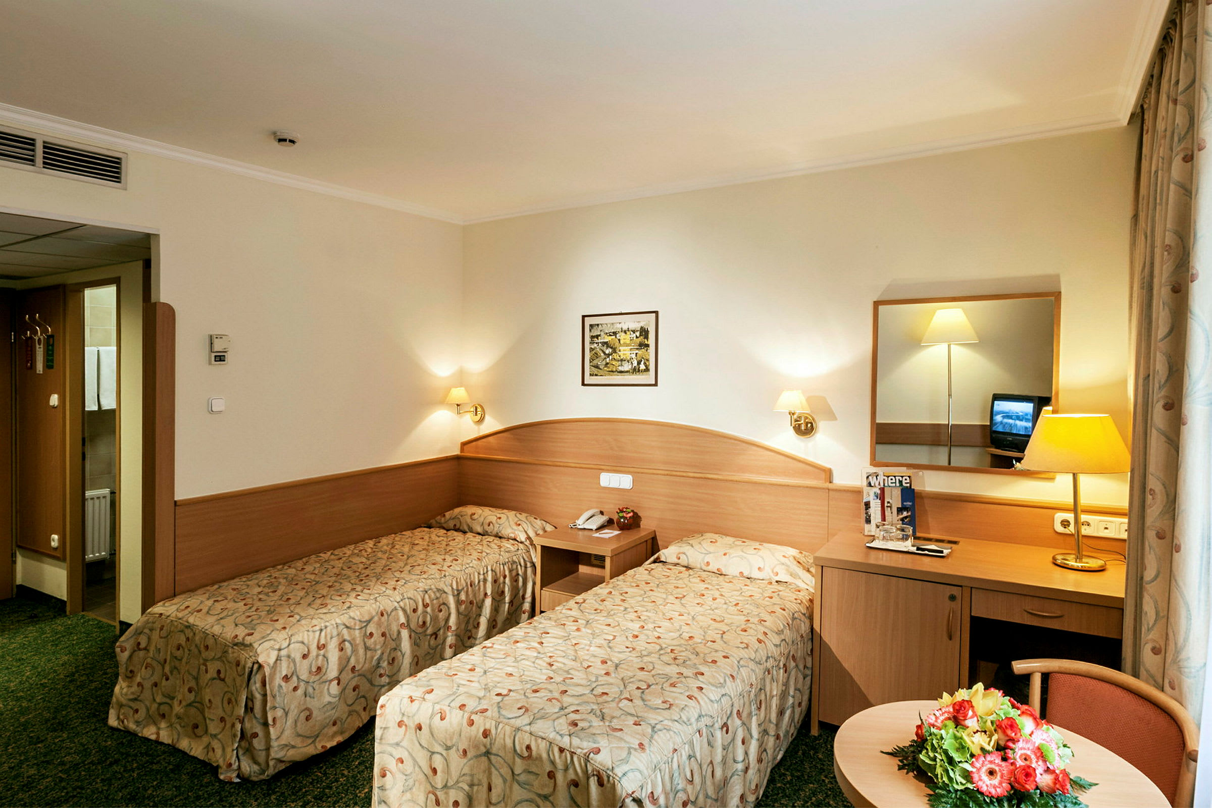Bild av ett hotellrum med två enkelsängar, ett skrivbord med en spegel och en liten sittgrupp. (AI-genererad text)