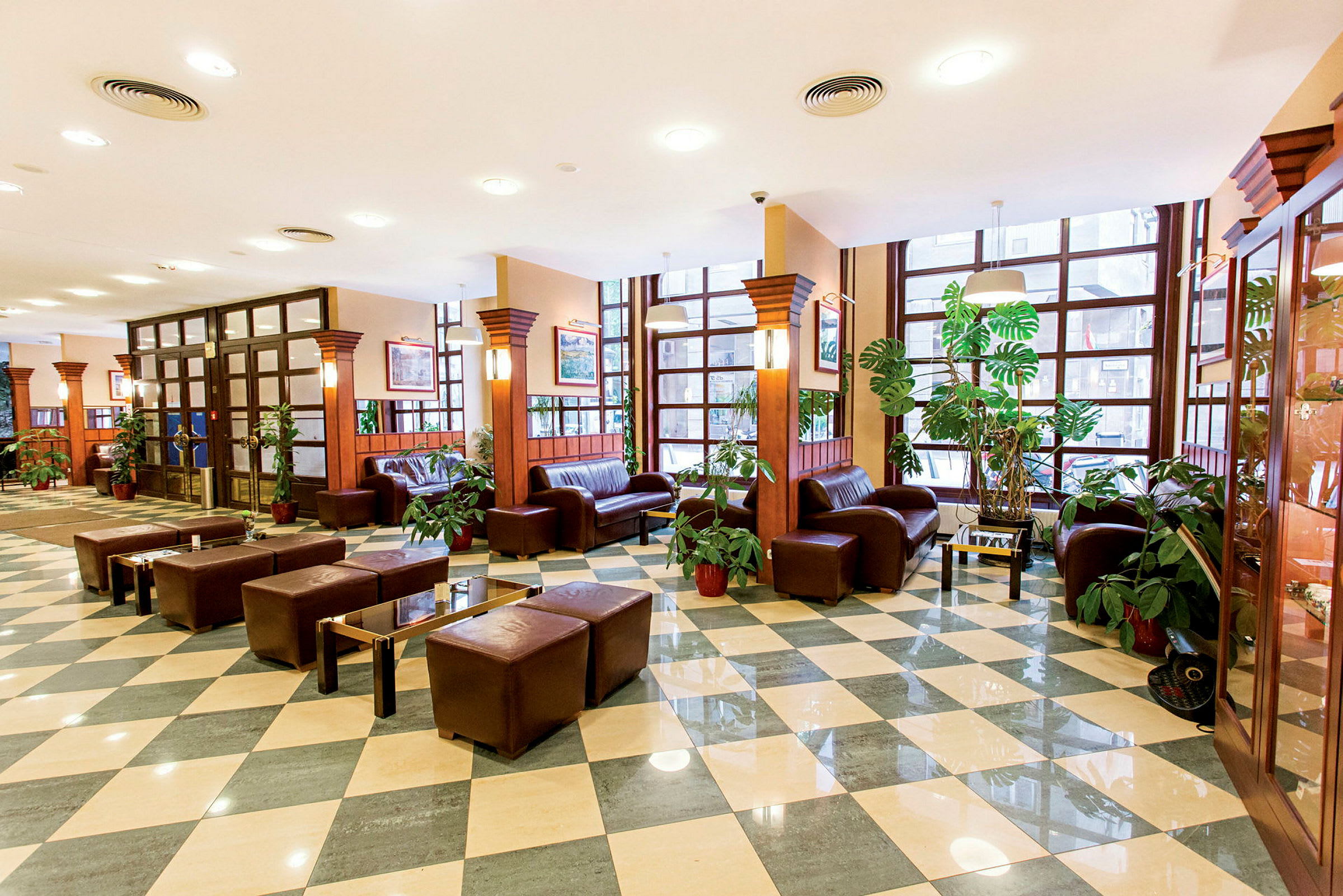 Hotellets lobby med bruna lädermöbler och gröna växter. (AI-genererad text)