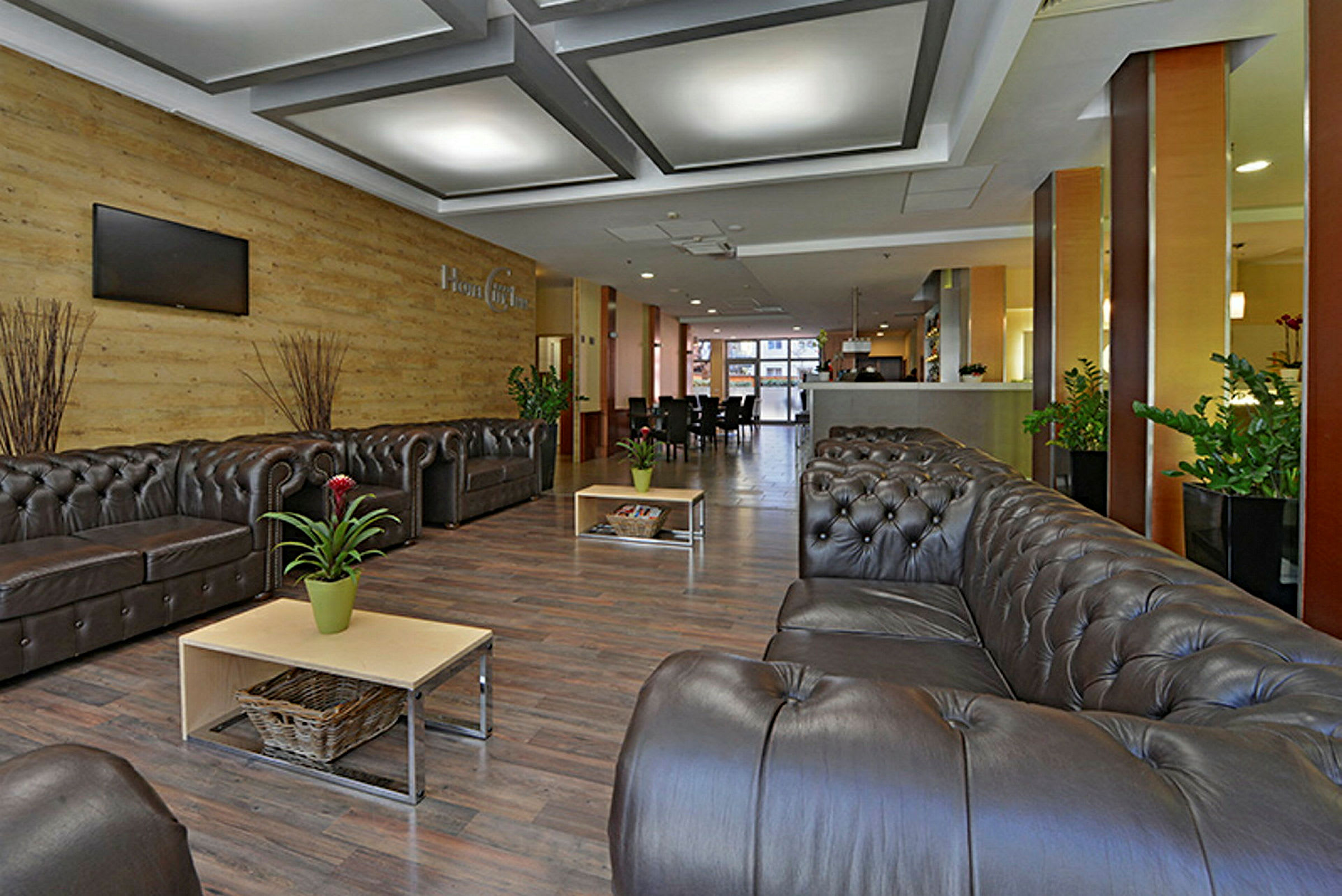 Ett hotellobby med bekväma soffor, soffbord, krukväxter och modern inredning. (AI-genererad text)