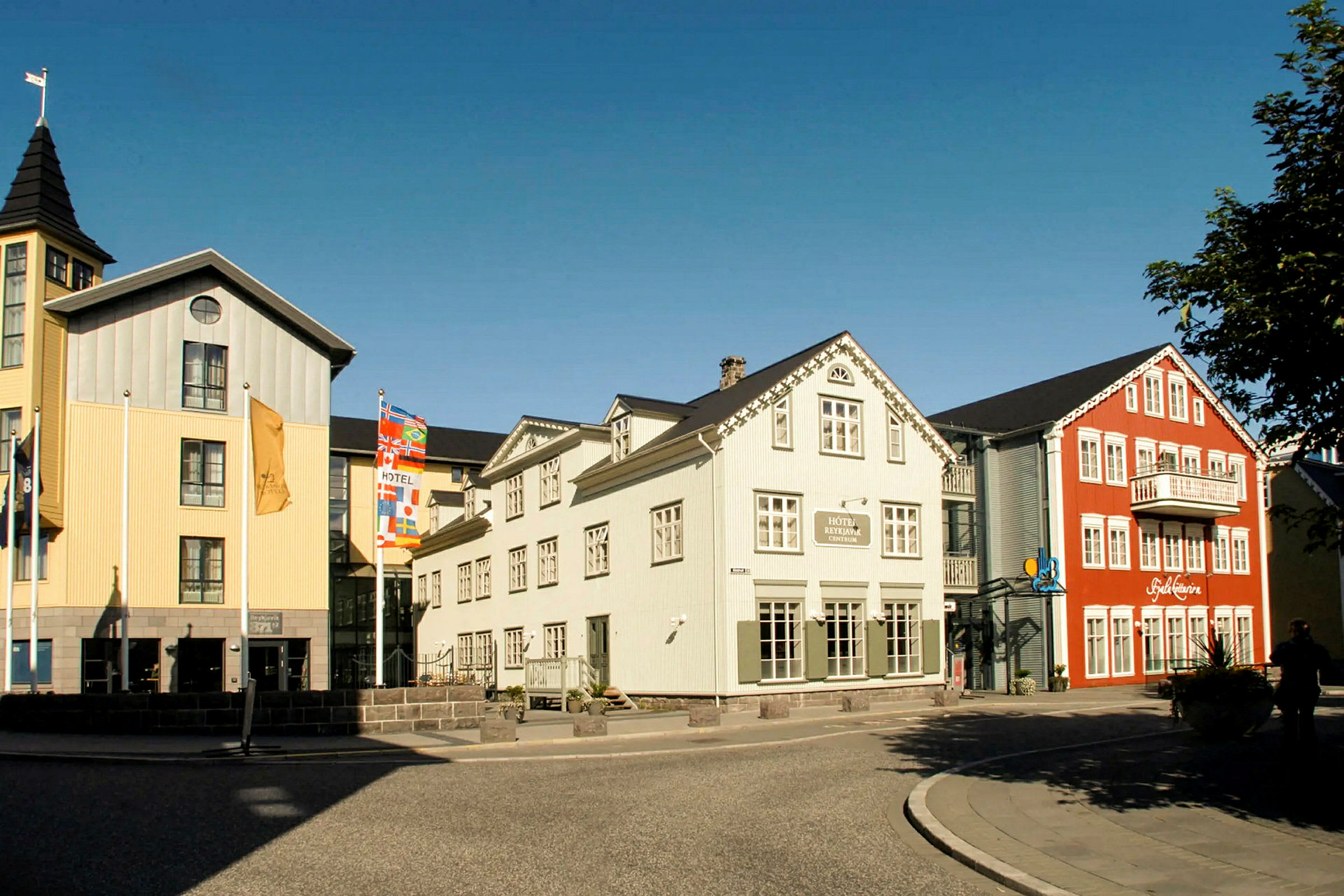 Bild av färgglada byggnader med hotell och restaurang nära en gata med trottoar. (AI-genererad text)