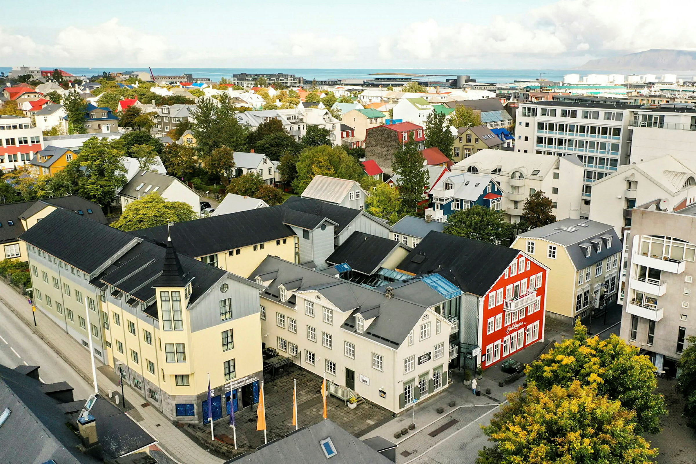 Flygbild över en stad med färgglada byggnader och grönska. (AI-genererad text)