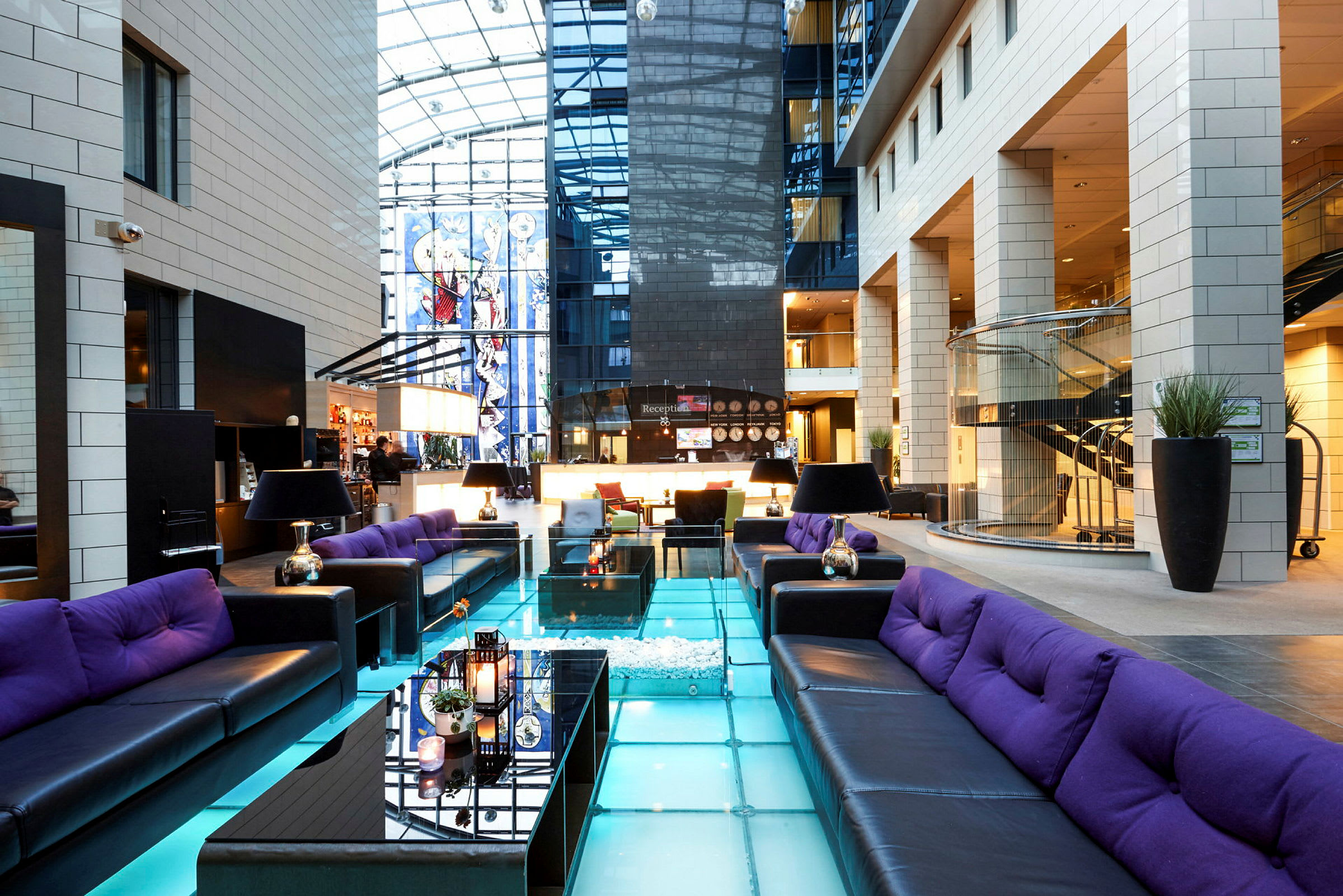 Ett modernt hotellobby med sittgrupper och glasgolv. (AI-genererad text)