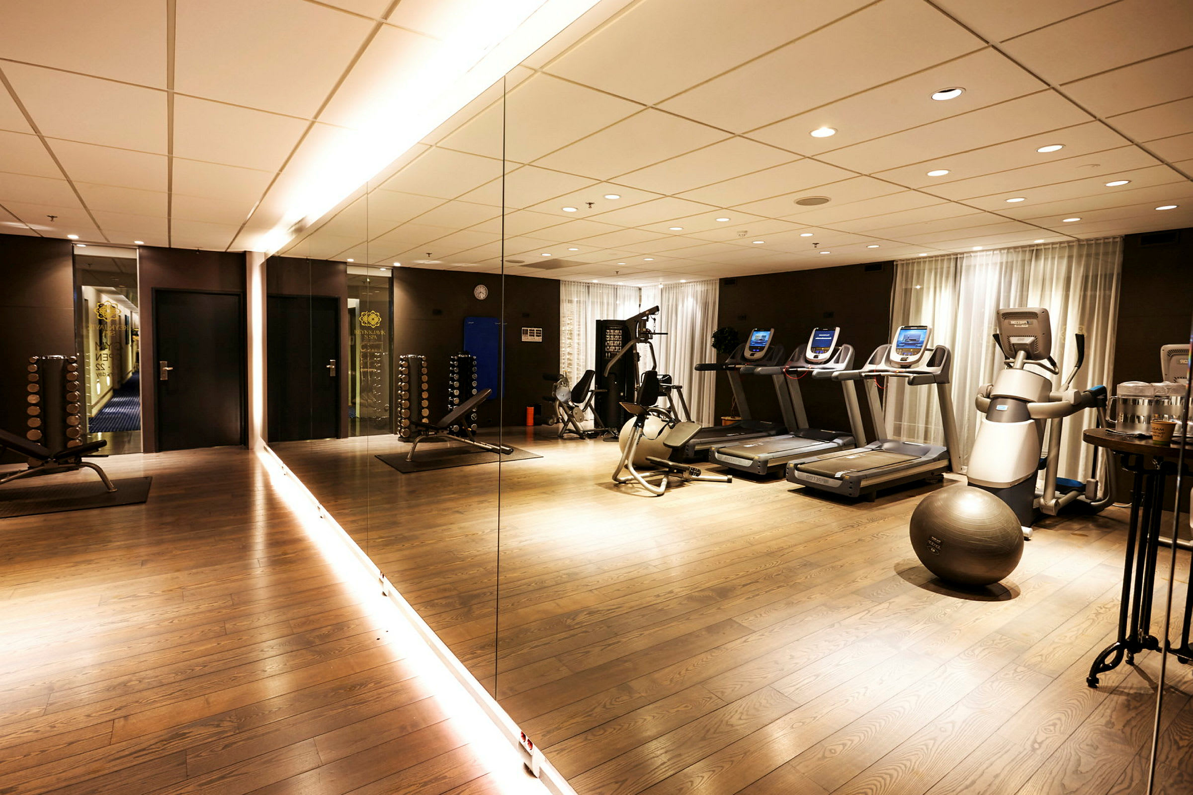 Gym med spegelvägg, träningsmaskiner och gymutrustning. (AI-genererad text)