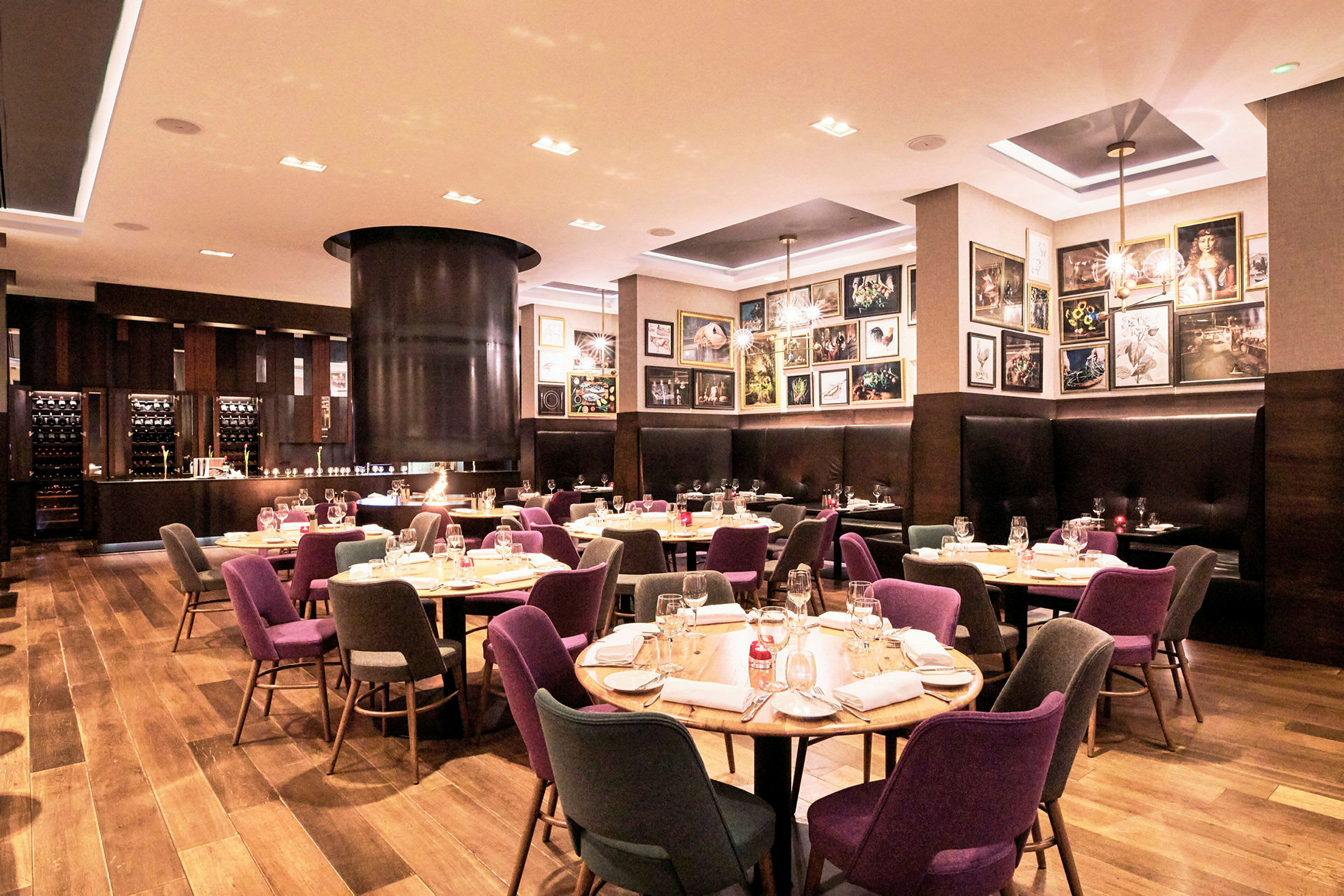 Ett väl upplyst restauranginteriör med dukade bord, färgglada stolar och en mysig atmosfär. (AI-genererad text)