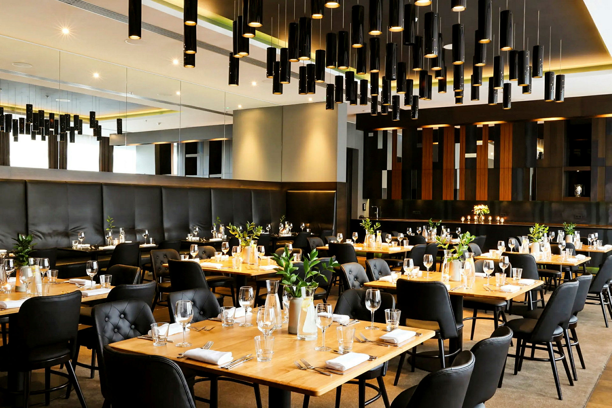 En elegant restaurang med uppsatta bord, svarta stolar och träbord, och modern ljusdesign. (AI-genererad text)