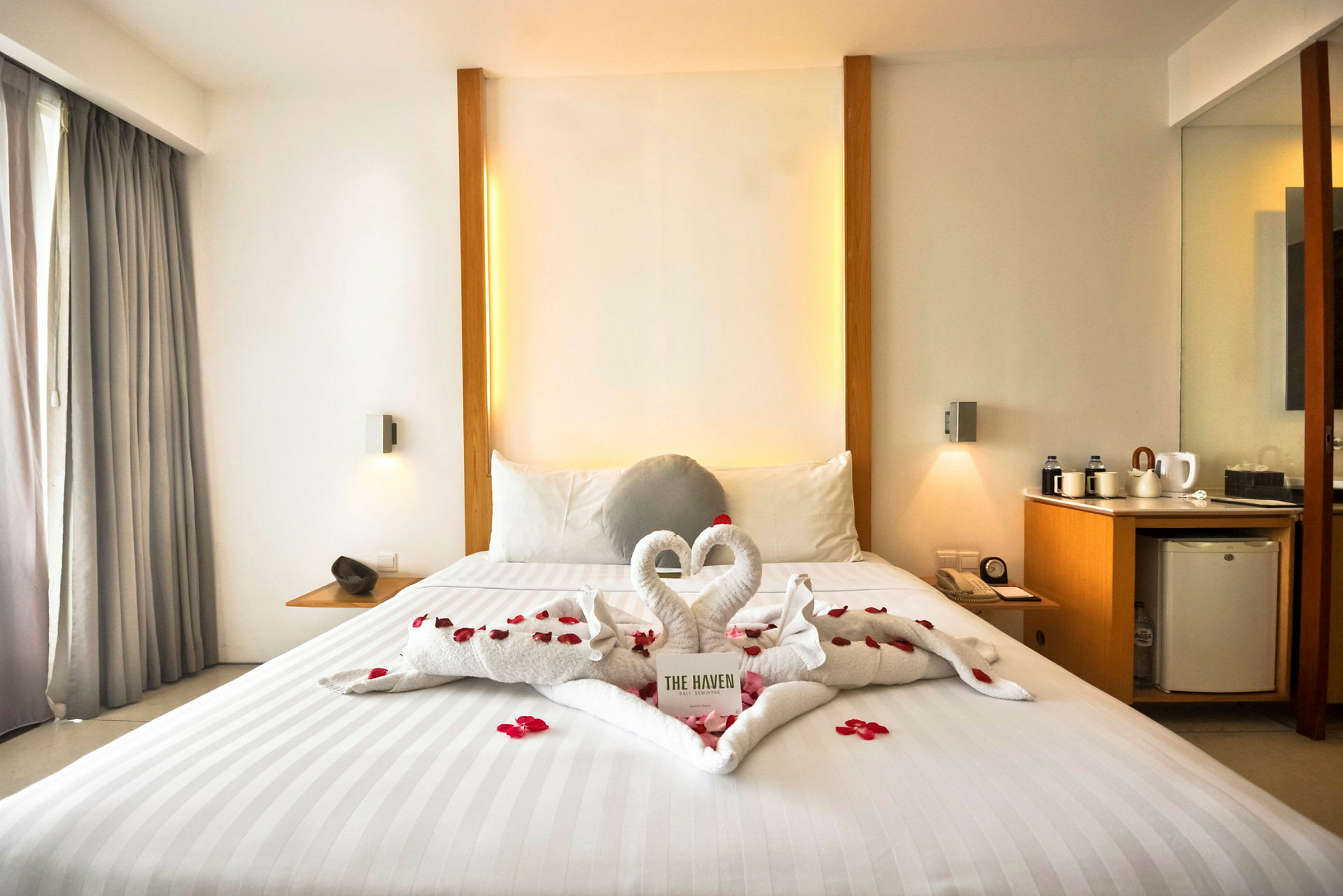 Hotellrum med en uppbäddad säng, dekorerad med handdukar formade som svanar och rosenblad. (AI-genererad text)
