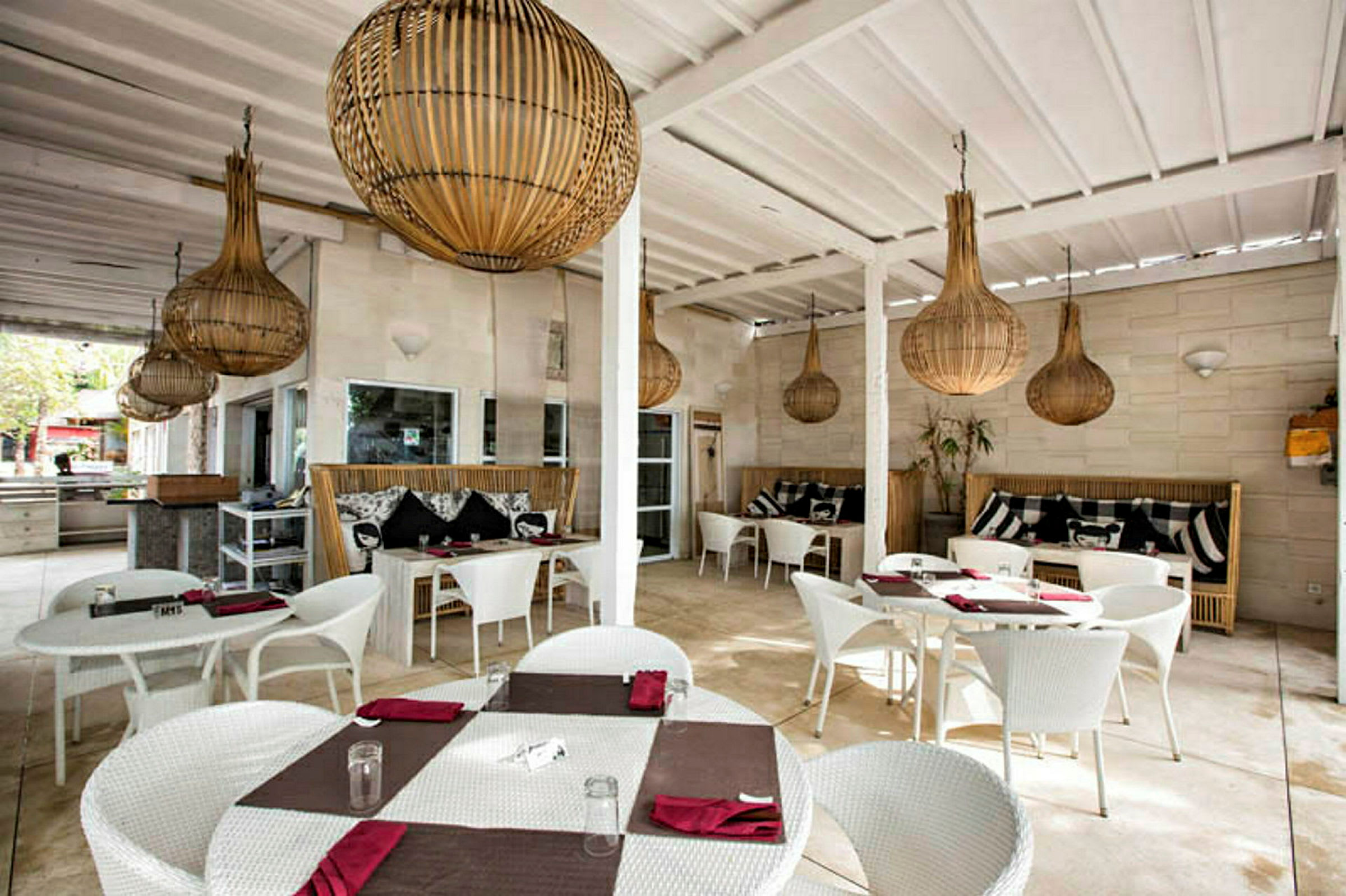 Restaurangområde med vita bord och stolar samt dekorativa lampor i taket. (AI-genererad text)