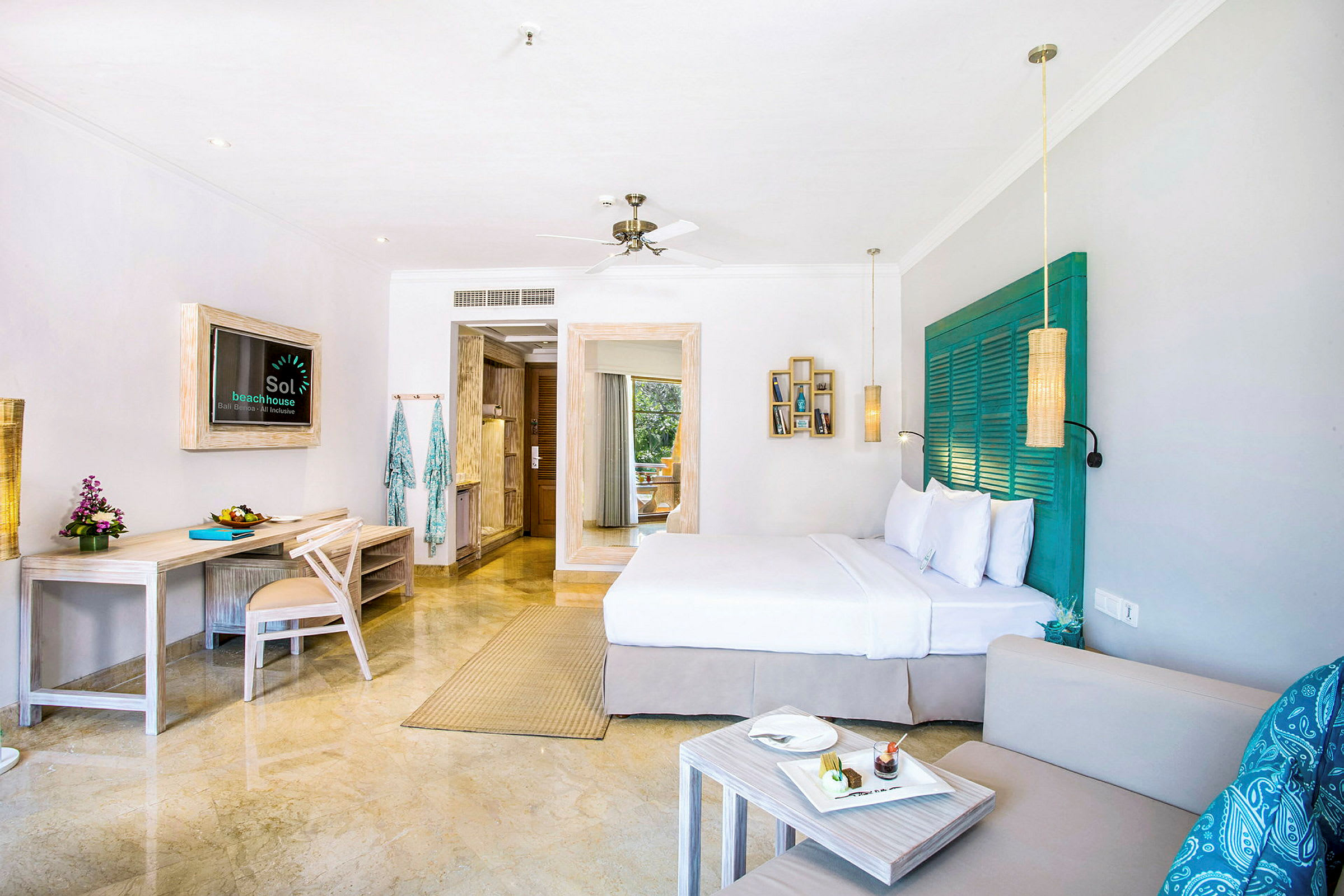 Ett ljust hotellrum med en dubbelsäng, skrivbord, soffa och dekorativa detaljer. (AI-genererad text)