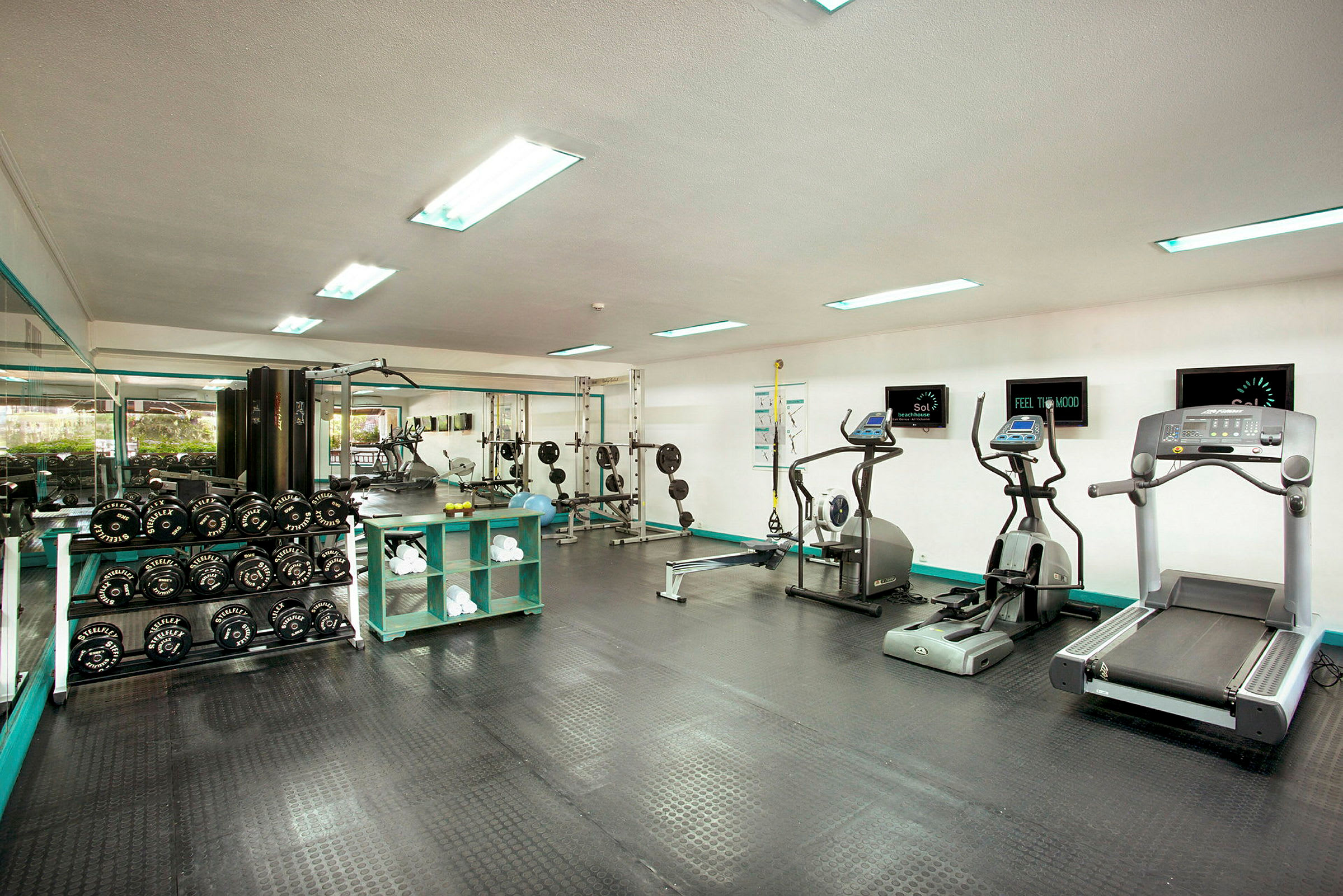 Gym med träningsmaskiner, fria vikter och spegelvägg. (AI-genererad text)