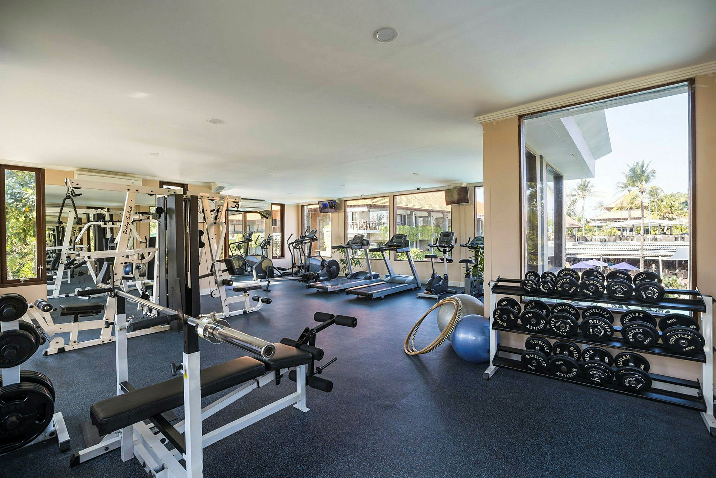 Gym med träningsutrustning och fönster som visar utsikt utomhus. (AI-genererad text)