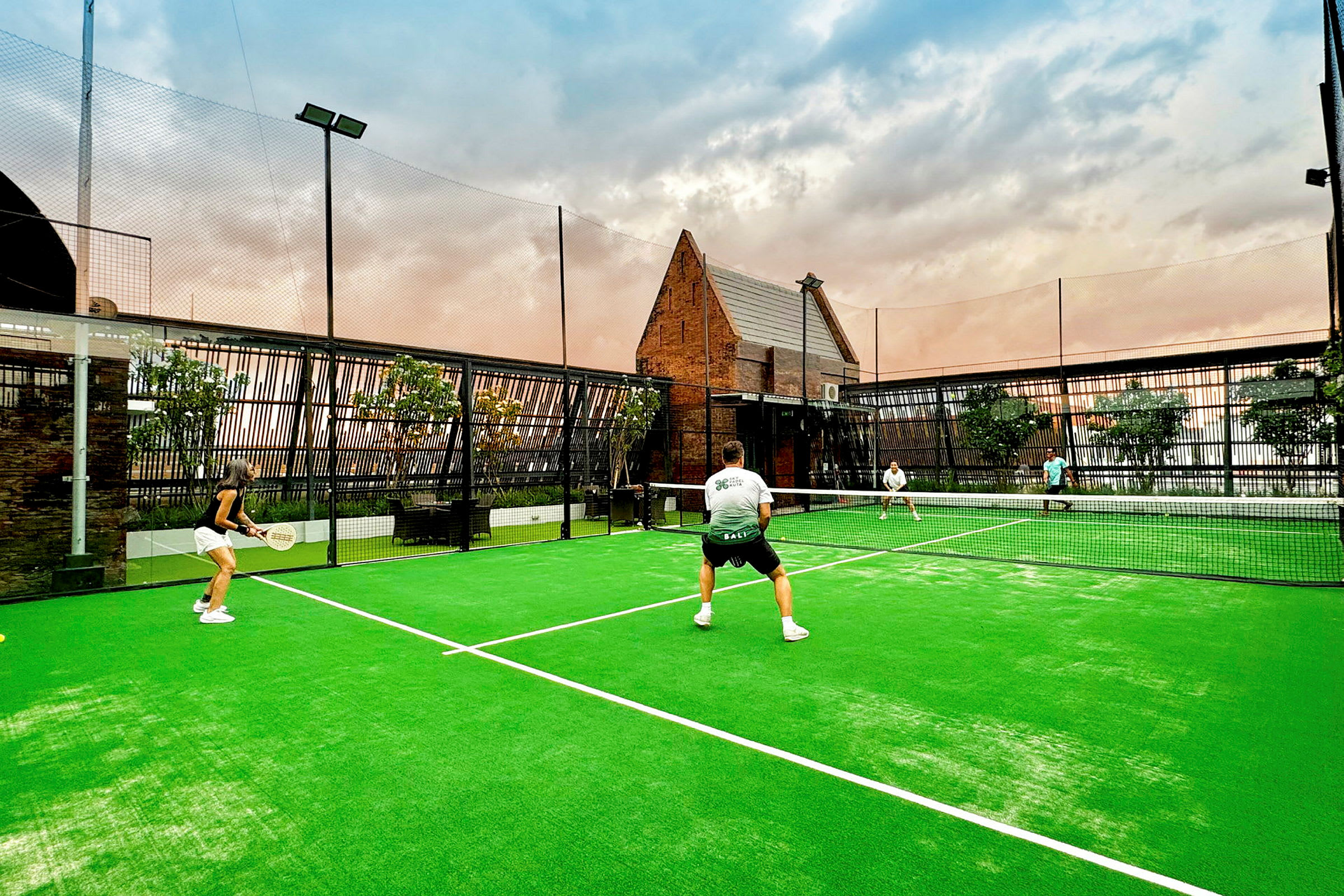 Fyra personer spelar padel på en utomhusbana med grönt underlag. (AI-genererad text)