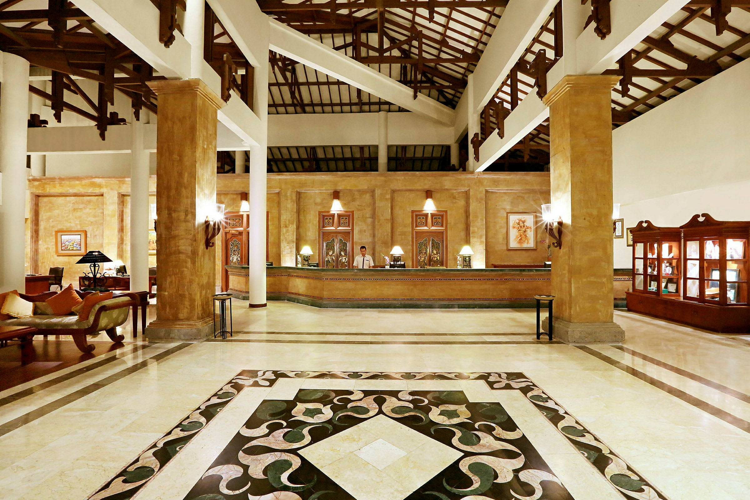 Ett hotellobby med glänsande marmorgolv, en reception försett med lampor och konst på väggen bakom. (AI-genererad text)