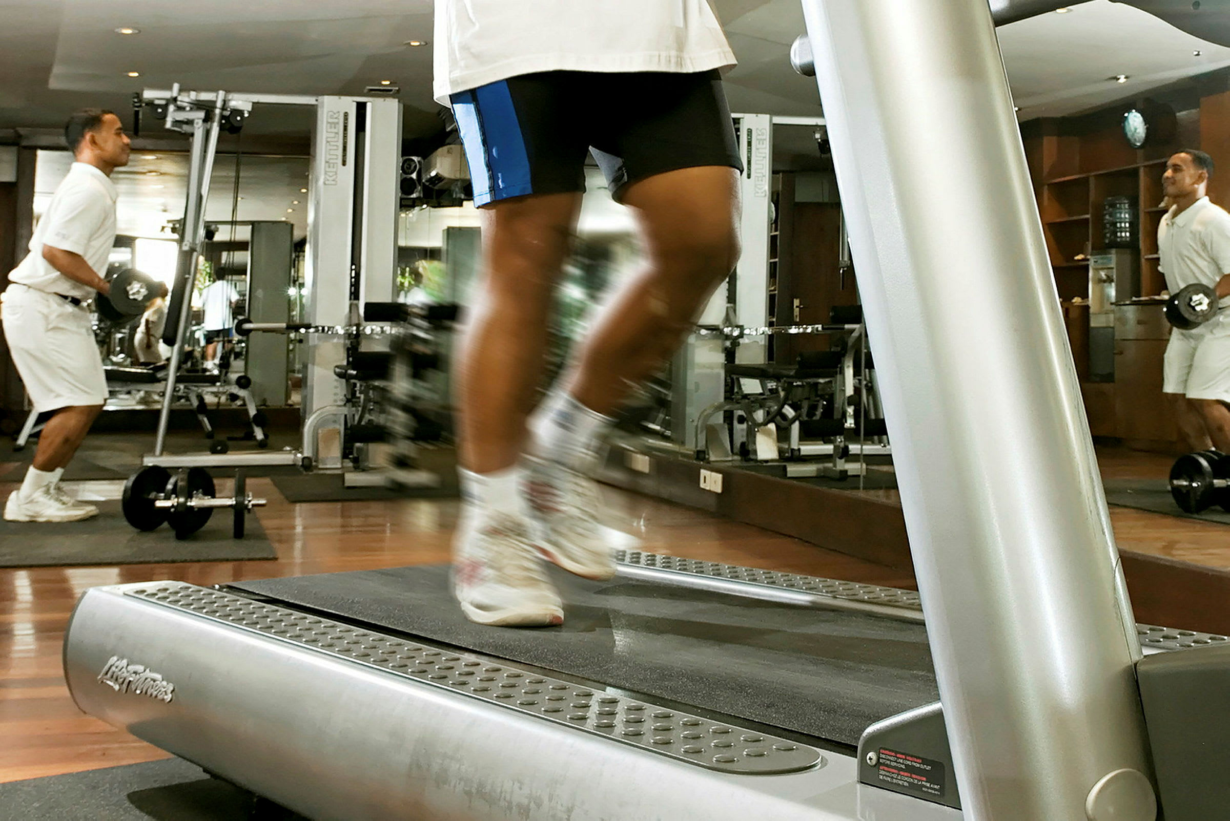 Ett gym med träningsmaskiner, där en person springer på ett löpband. (AI-genererad text)