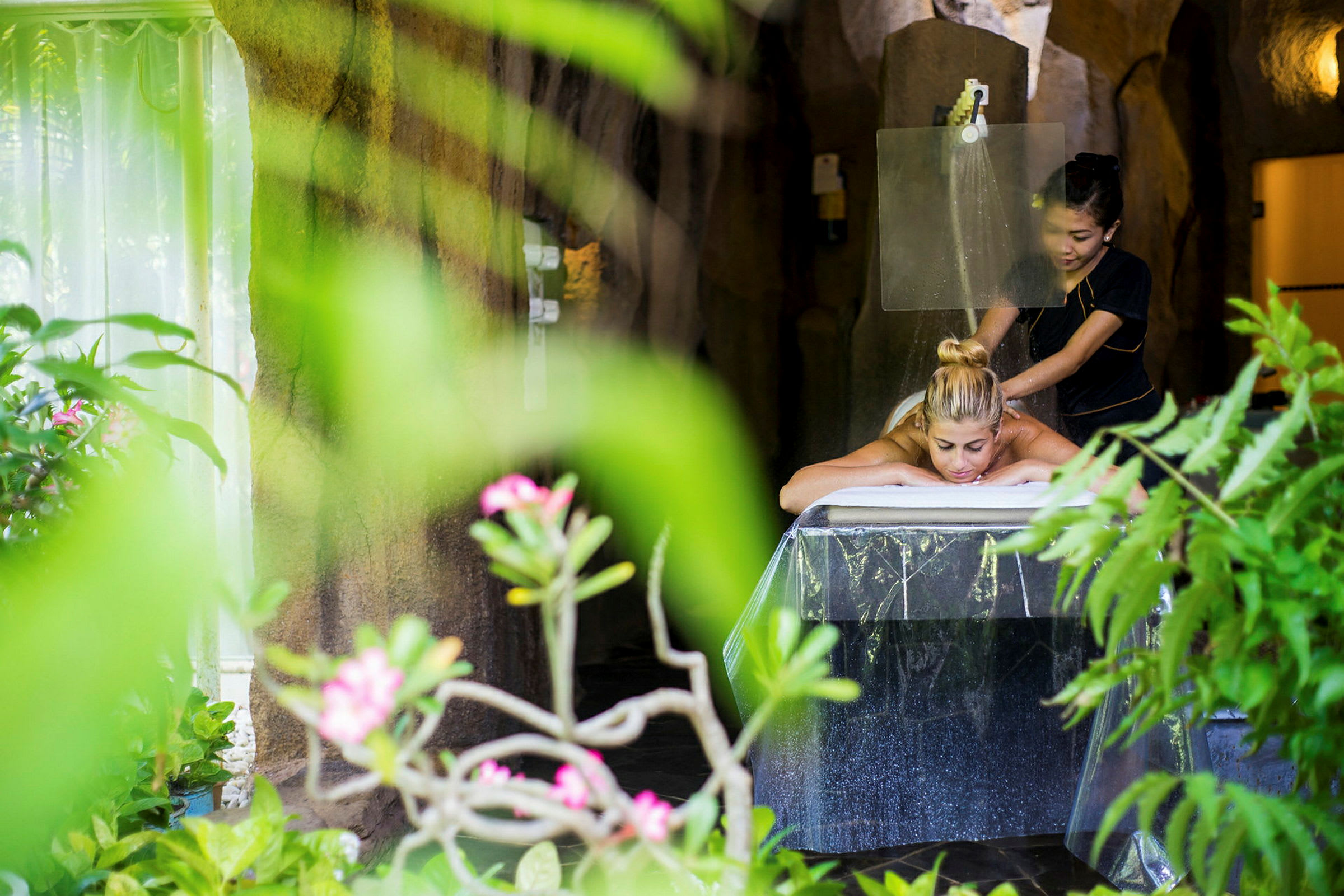 En person får massage i en atmosfär med naturliga inslag och grönska. (AI-genererad text)
