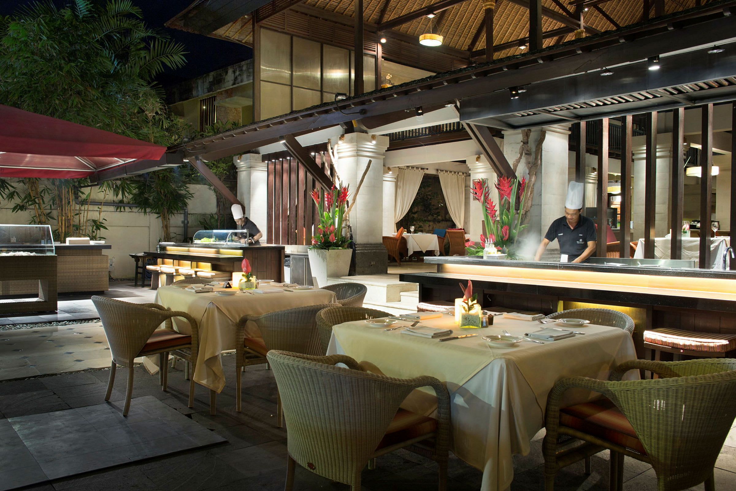 En utomhus restaurang med dukade bord och planteringar. (AI-genererad text)