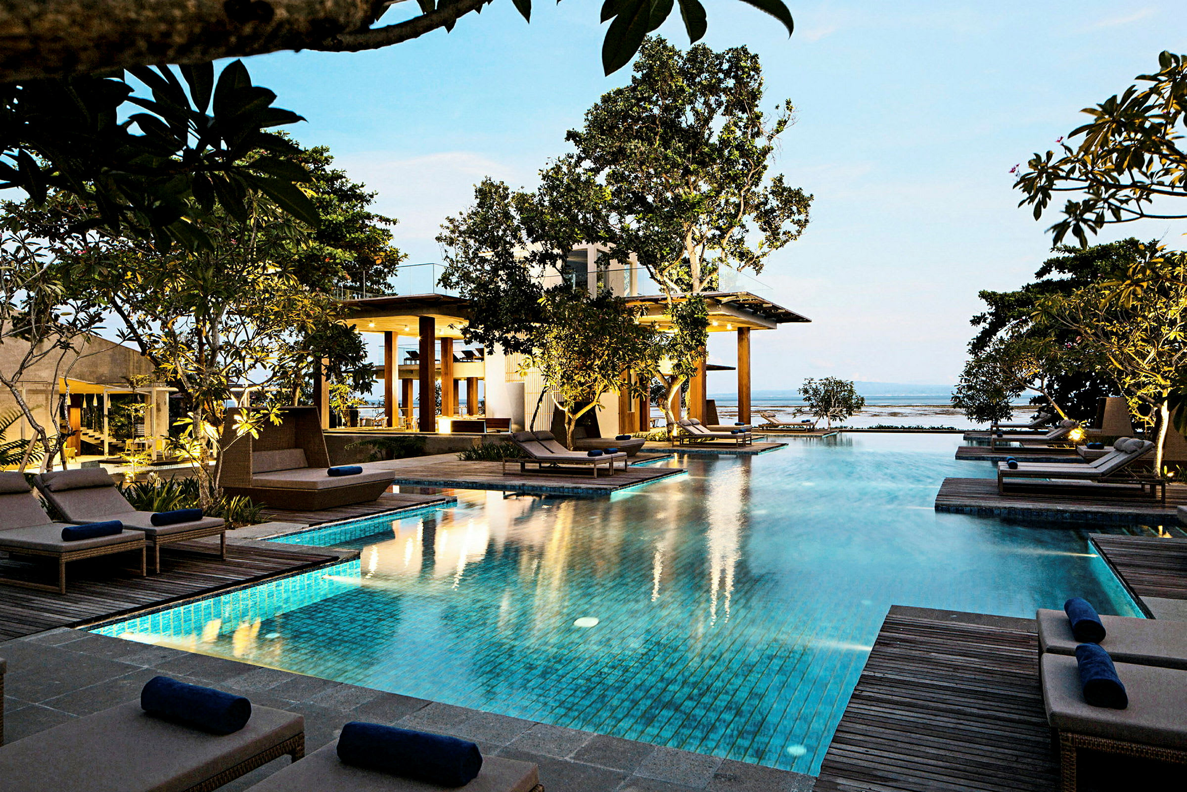 En lyxig pool omgiven av solstolar och grönska vid en modern resort. (AI-genererad text)