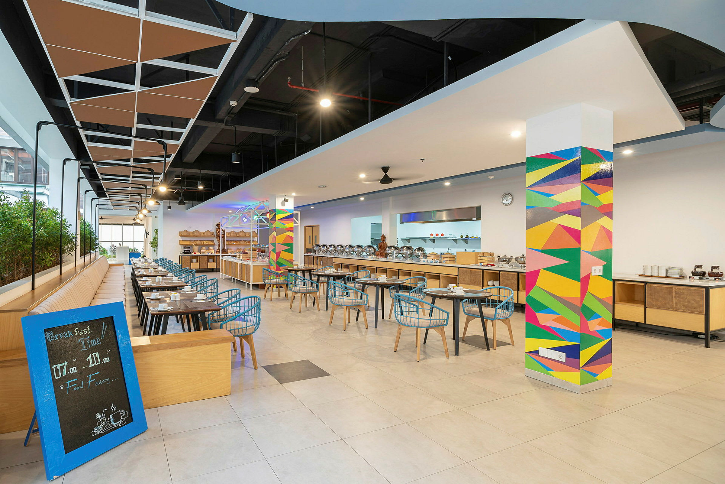 Interiör av en modern restaurang med färgglad väggdekoration och sittplatser arrangerade längs bord. (AI-genererad text)