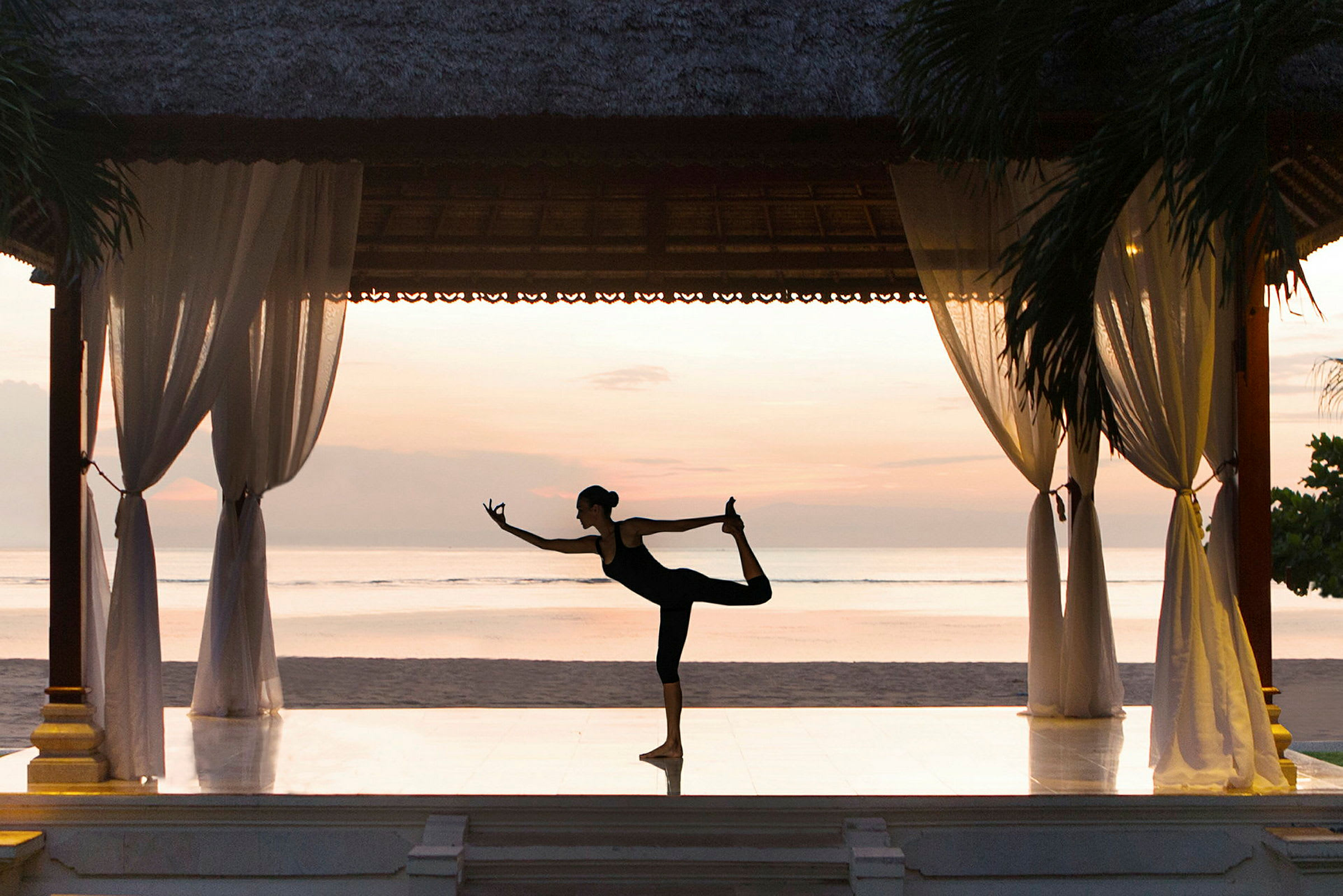 En person gör yoga på en paviljong vid stranden med en lugnande horisont i bakgrunden. (AI-genererad text)