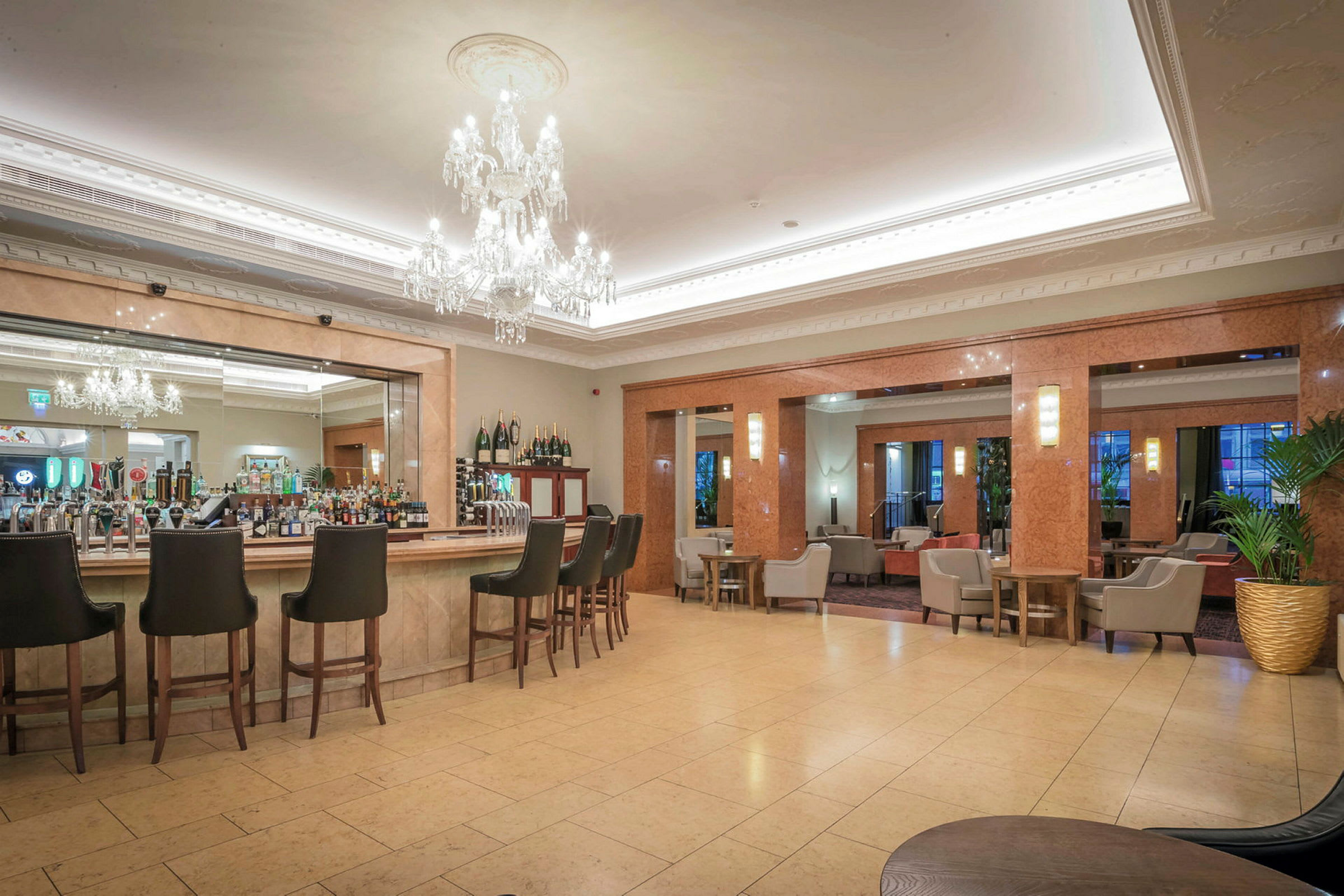 Modernt hotellbarområde med höga stolar och kristallkronor. (AI-genererad text)
