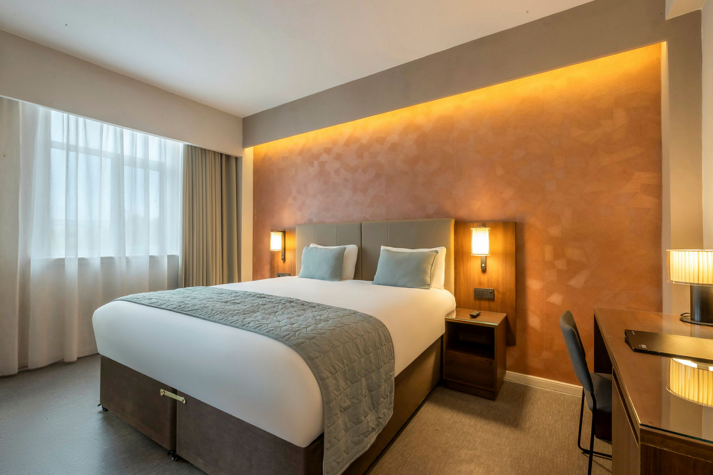 Ett hotellrum med en stor säng, två sängbord och ett skrivbord. (AI-genererad text)
