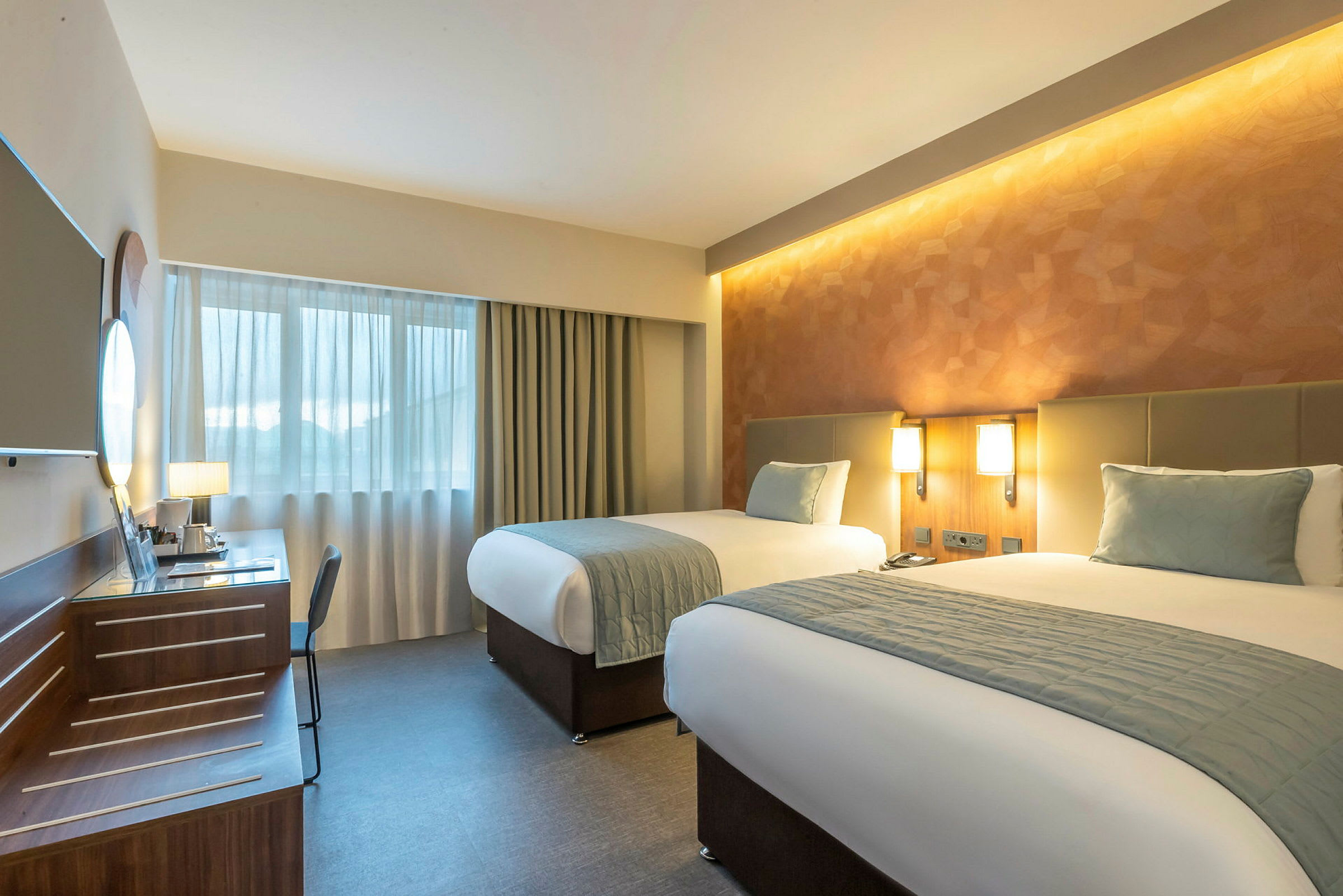 Ett hotellrum med två enkelsängar, skrivbord och fönster. (AI-genererad text)
