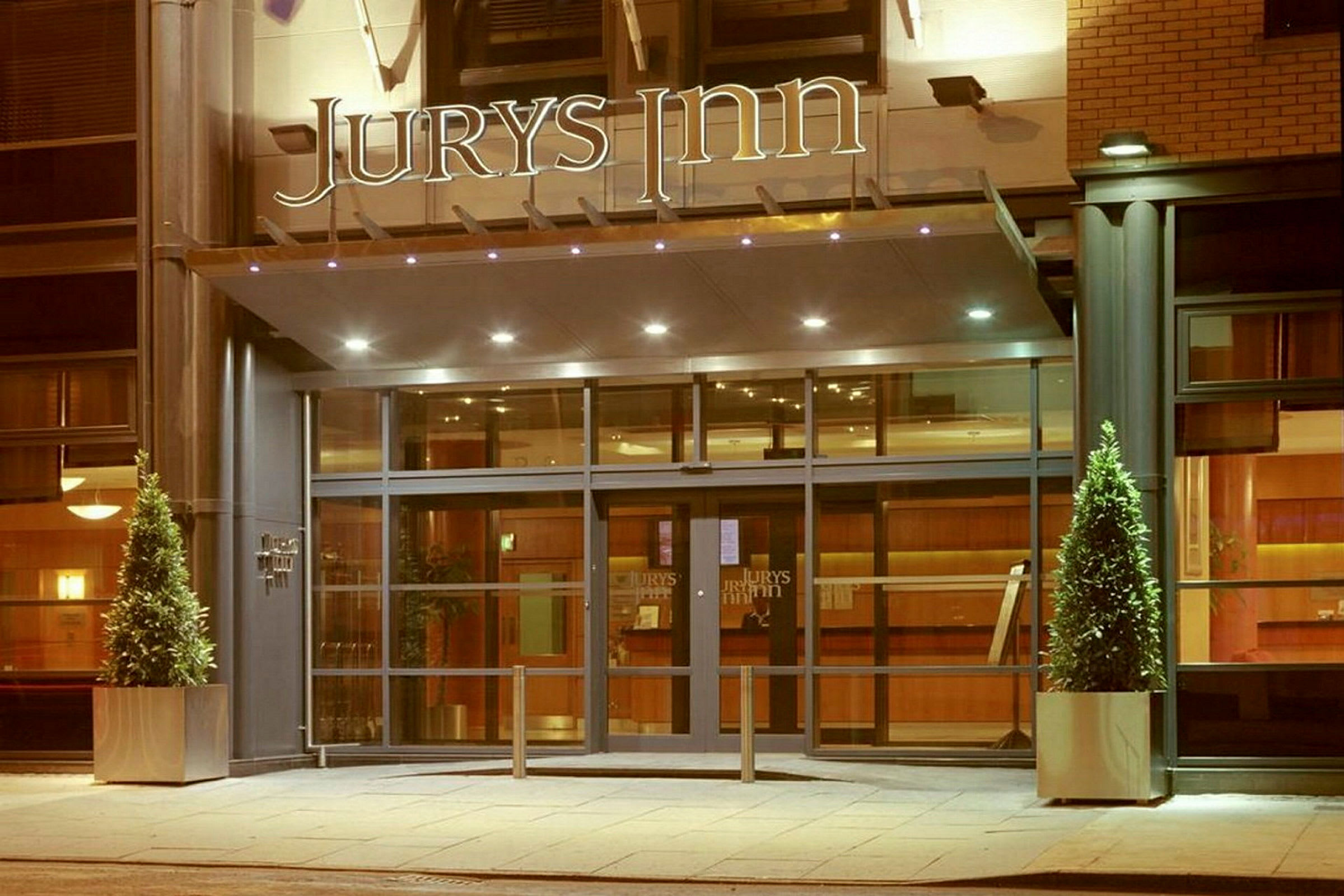 Hotellentré med glasdörrar och skylten 'Jurys Inn' ovanför. (AI-genererad text)