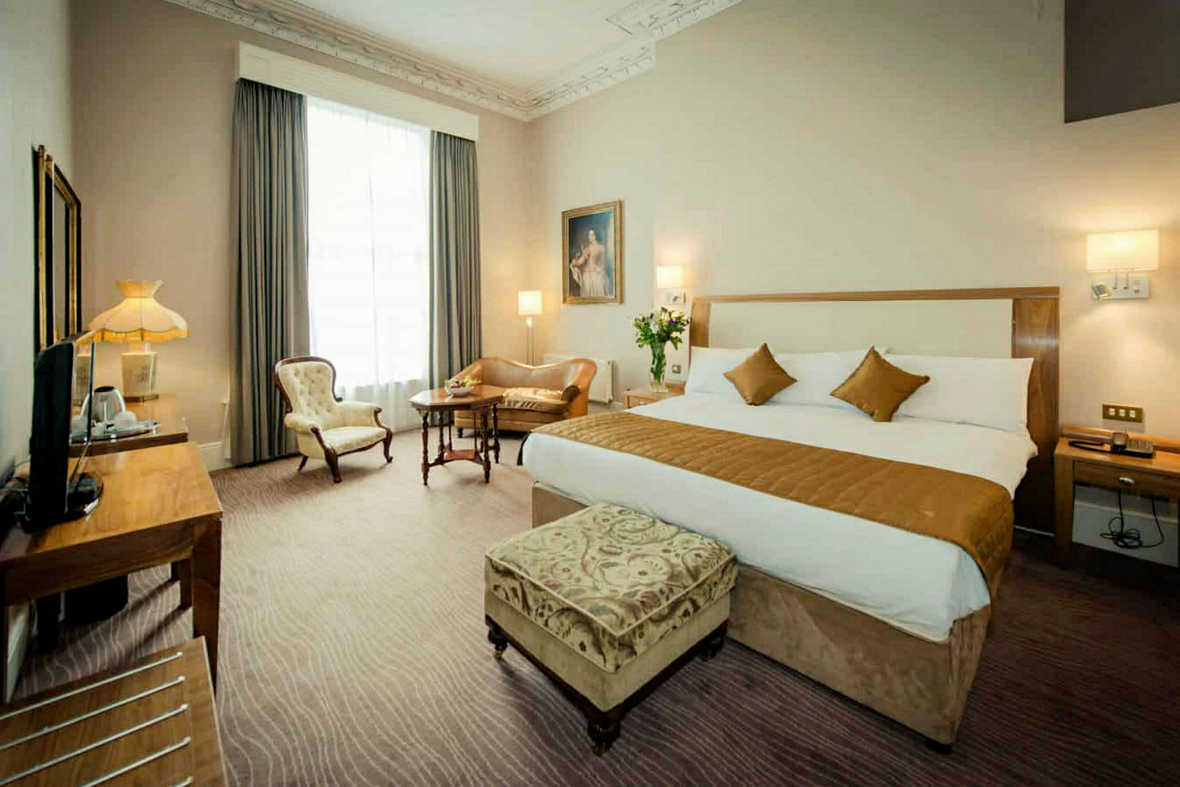 Hotellrum med stor säng och sittmöbler. (AI-genererad text)